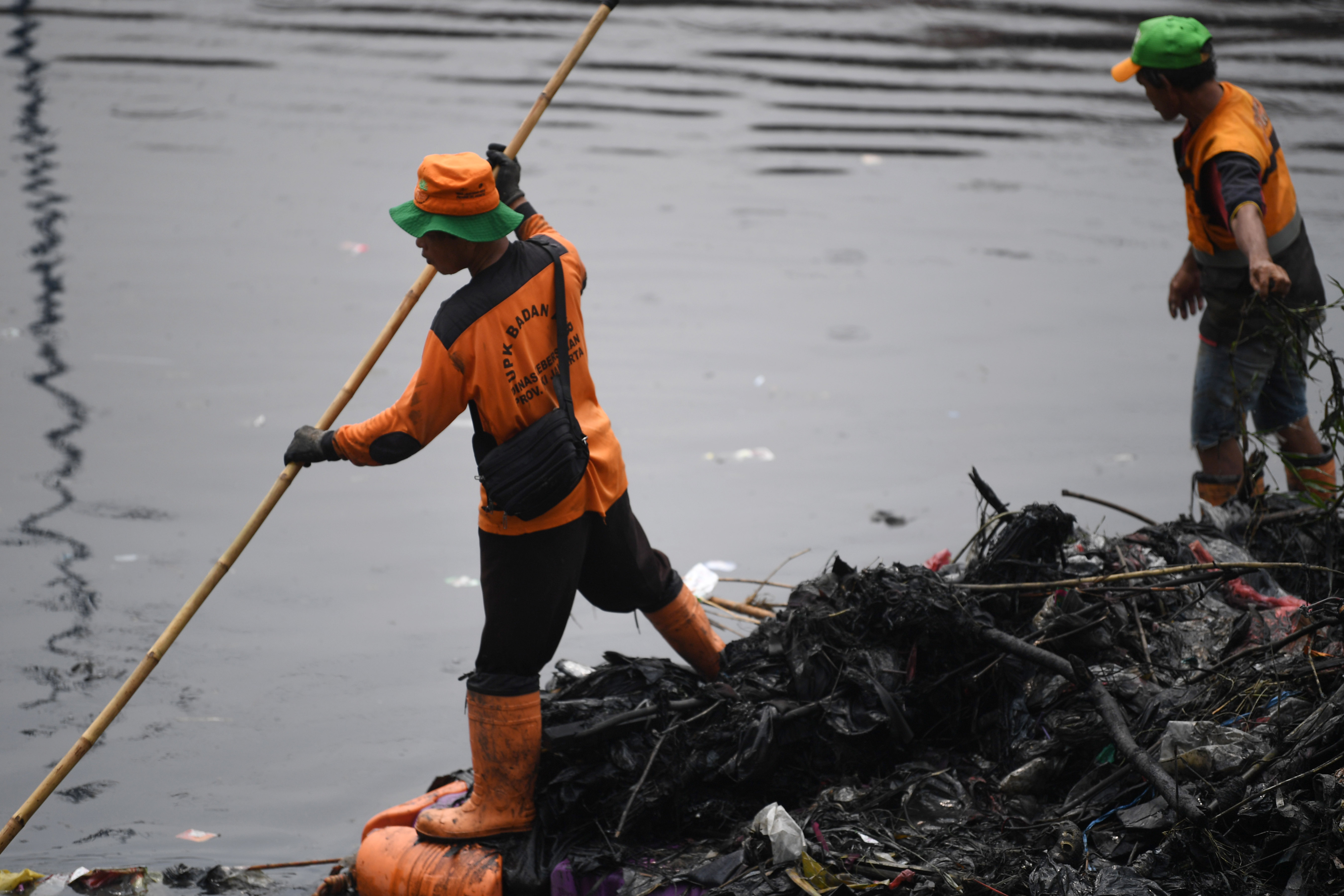 Petugas kebersihan mengambil sampah di aliran sungai Kanal Bajir Barat, Tanah Abang, Jakarta, Kamis (5/9/2019)