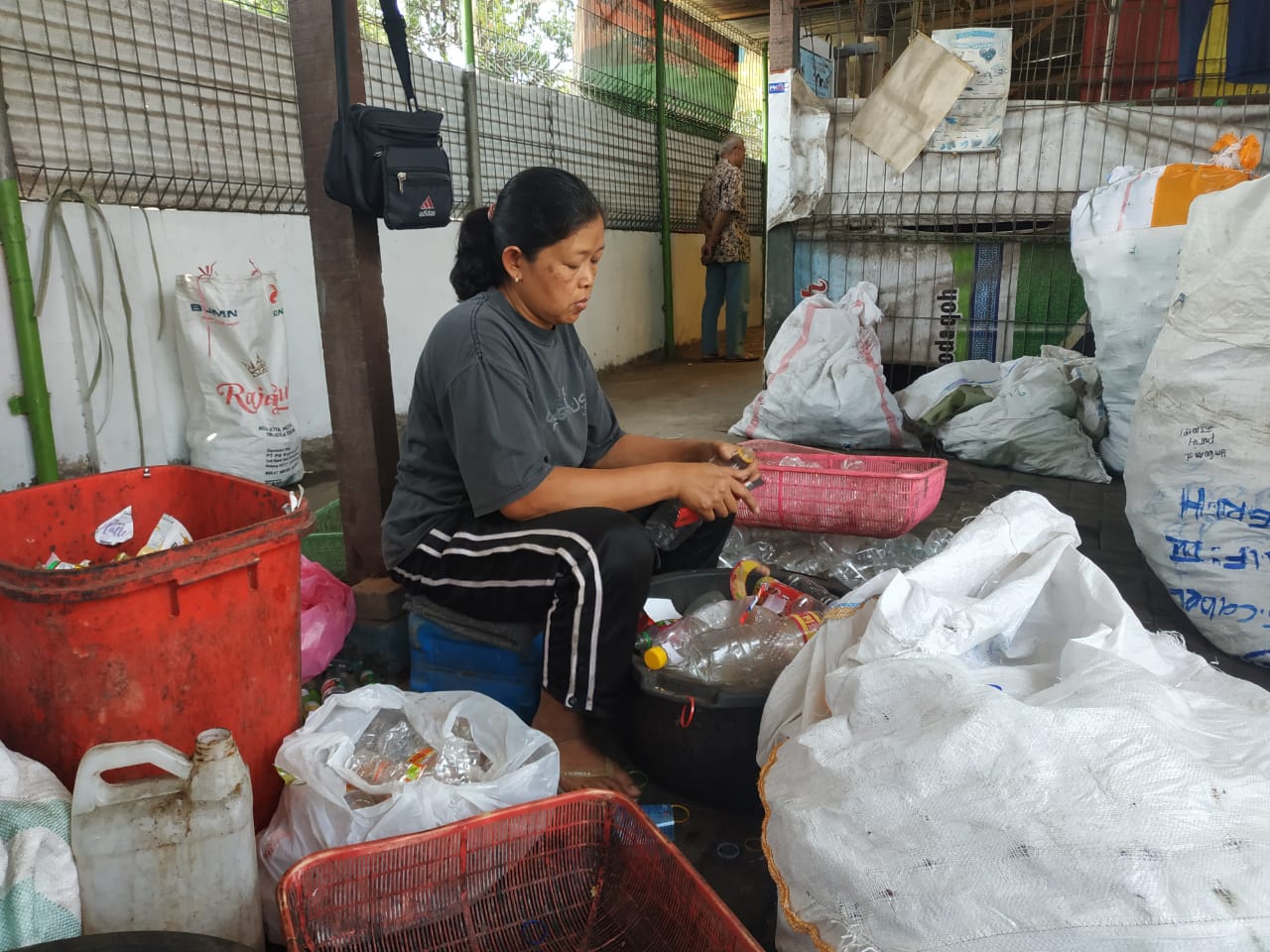 Seorang karyawan Bank Sampah Kota Malang sedang memilah jenis-jenis sampah yang siap dijual.