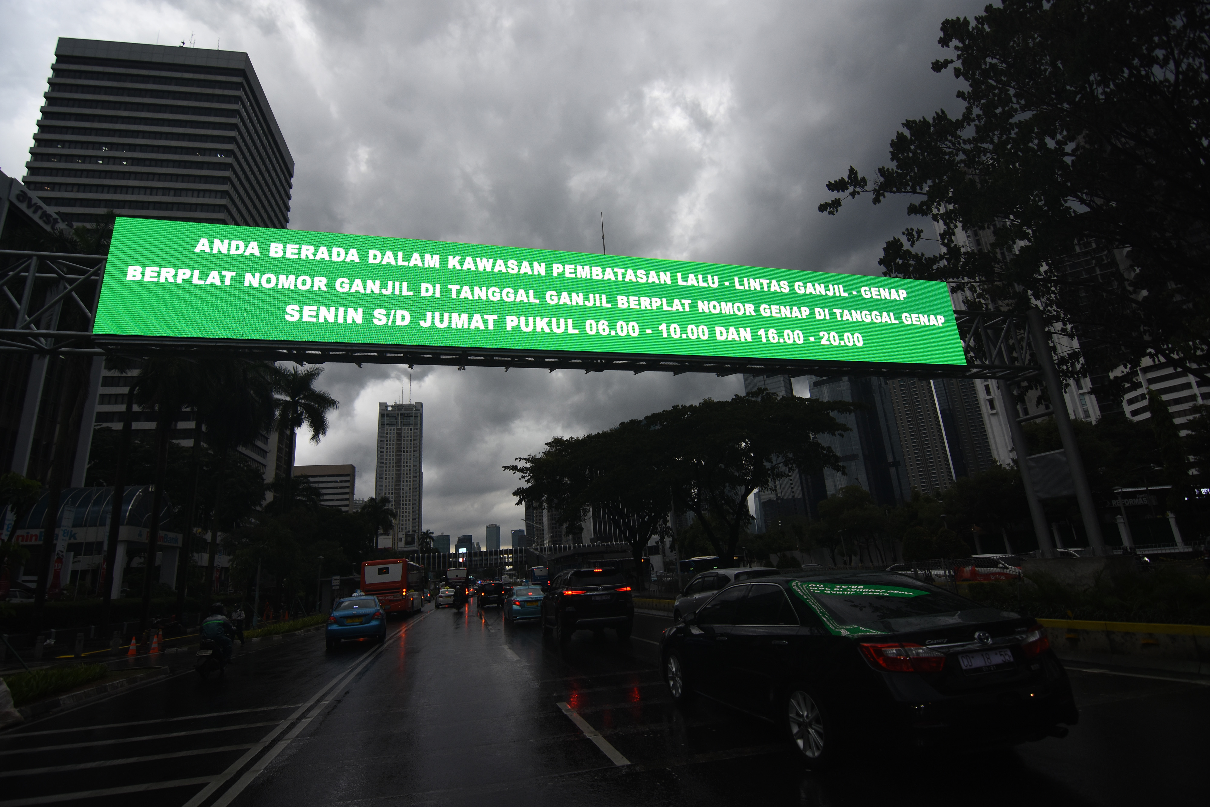Kendaraan melintas di dekat papan informasi kebijakan sistem pembatasan kendaraan bermotor  di kawasan Sudirman, Jakarta