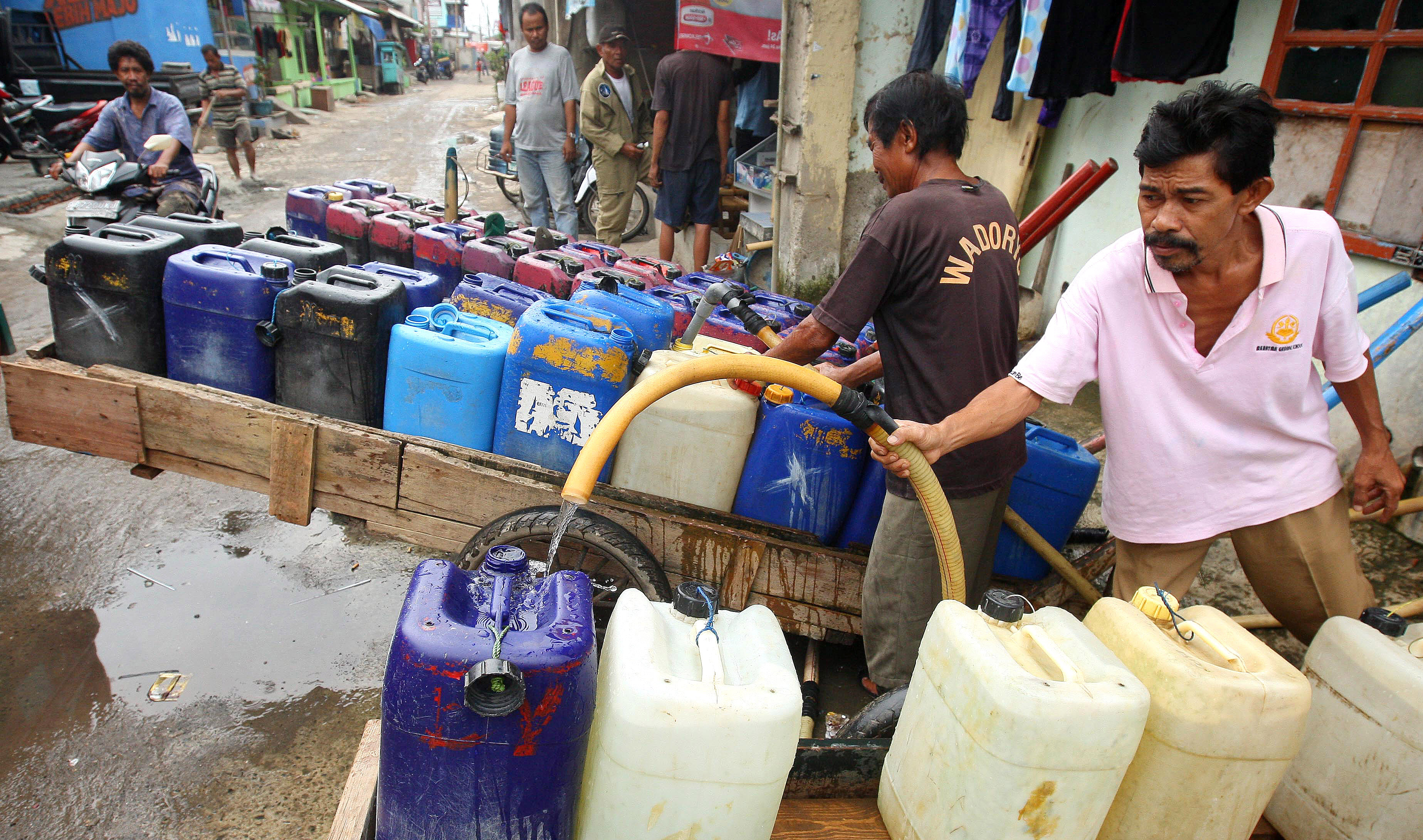 Penjual air keliling mengisi air bersih ke dalam jerigen untuk disalurkan kepada langganannya di kawasan Penjaringan, Jakarta Utara