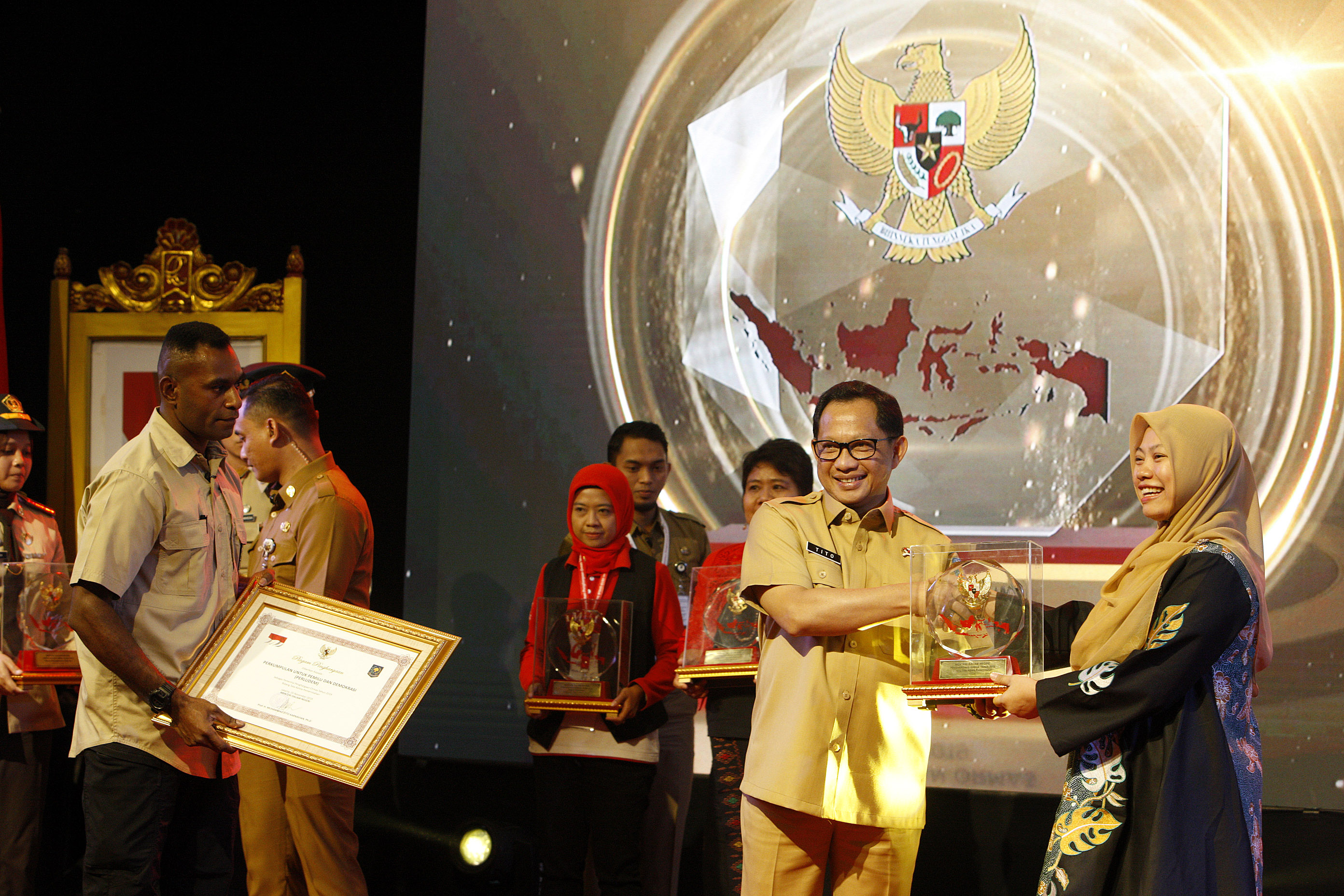 Menteri Dalam Negeri Tito Karnavian (kiri) menyerahkan penghargaan kepada Direktur Eksekutif Perludem Titi Anggraini dalam Ormas Award 2019