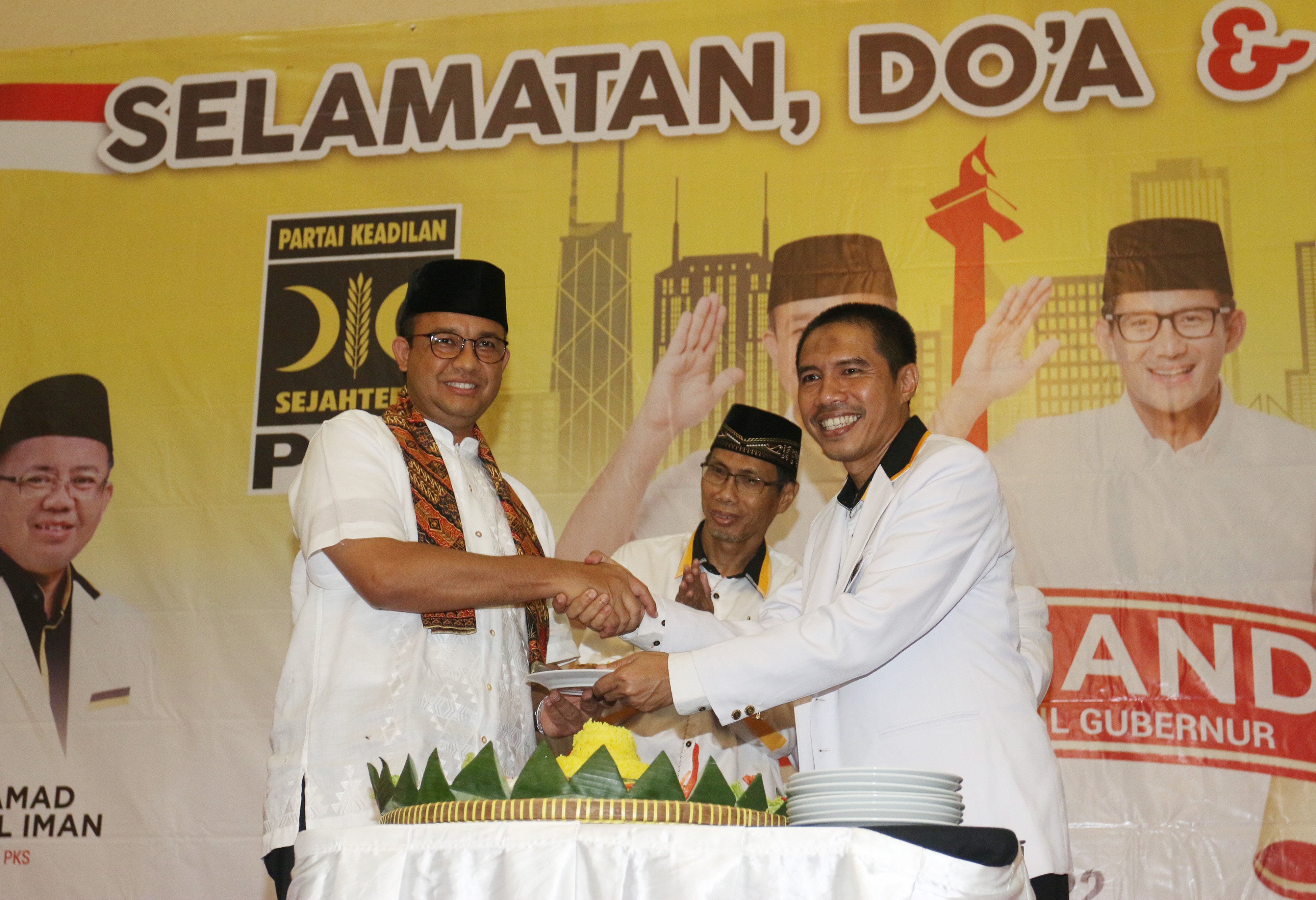 Ketua Umum DPW PKS DKI Jakarta Syakir Purnomo (kanan) memberikan potongan tumpeng kepada Gubernur DKI Jakarta Anies Baswedan