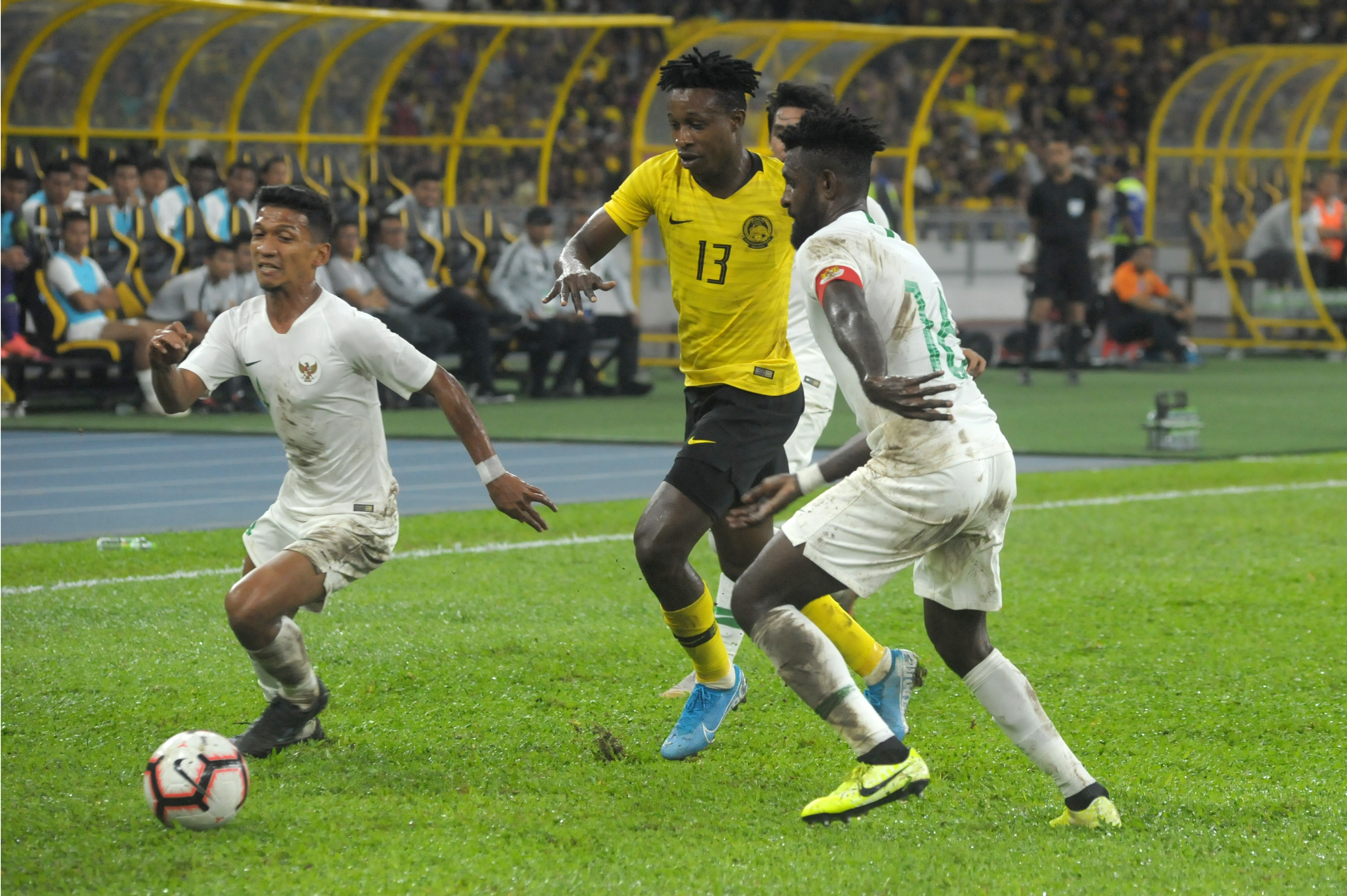 Pemain Indonesia Teuku Muhammad Ichsan (bawah) berebut bola dengan pemain Malaysia, Mohamadou Sumareh (tengah).