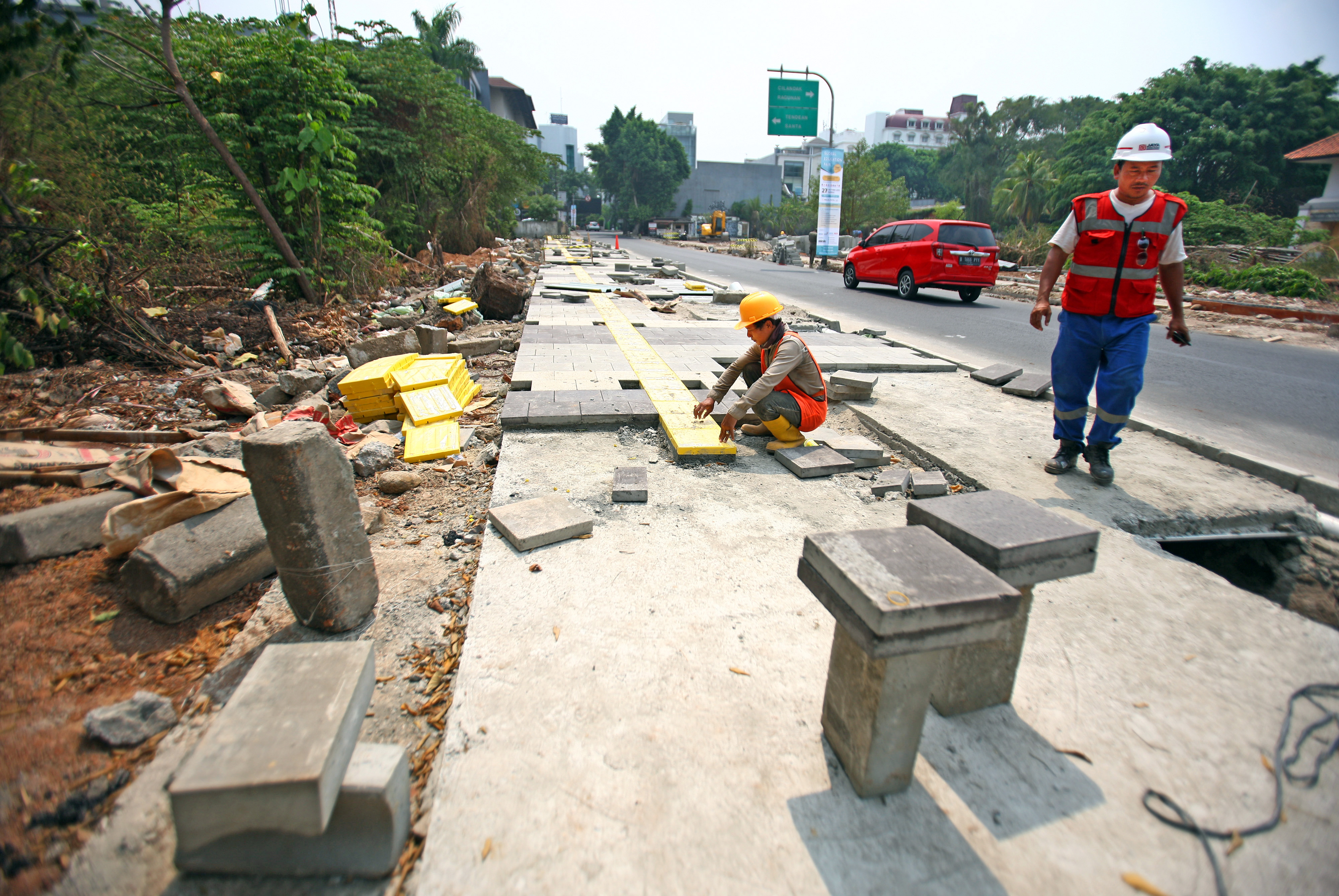 Pekerja sedang melaksanakan perbaikan trotoar di wilayah Kemang, Jakarta Selatan. 