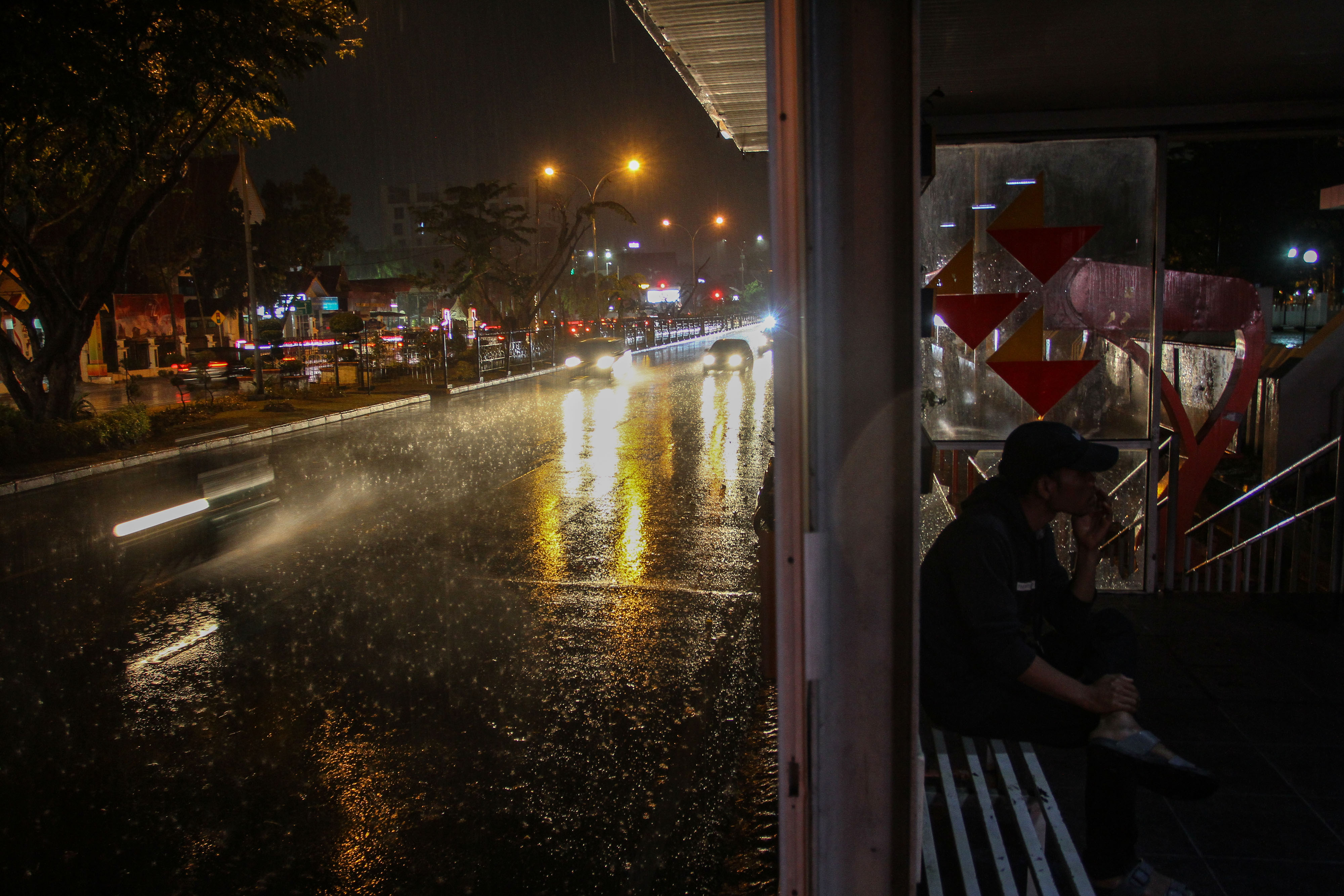 Seorang warga berada di halte Trans Metro Pekanbaru ketika menunggu hujan reda di Kota Pekanbaru, Riau.