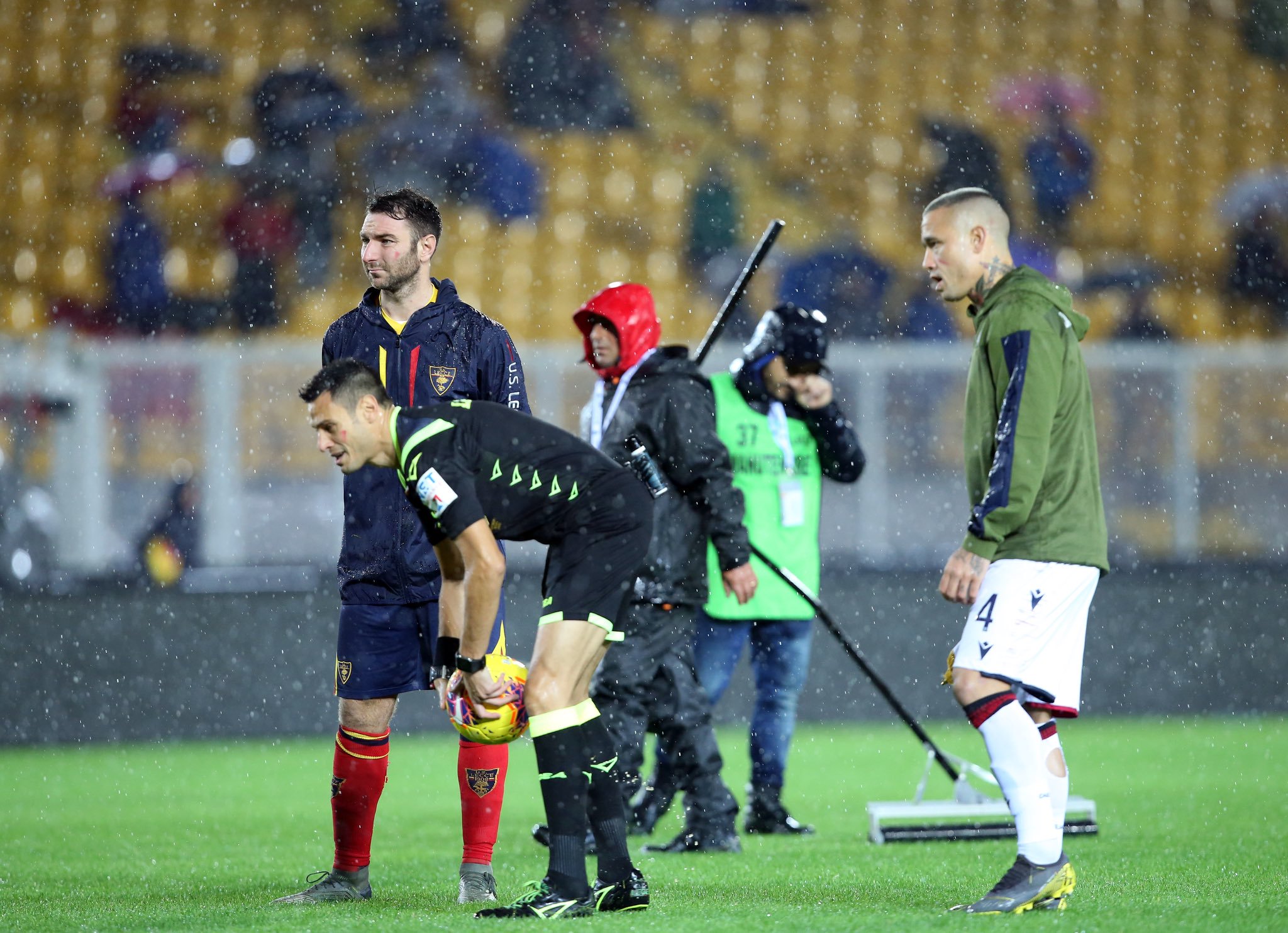 Wasit Maurizio Mariani (tengah) bersama kapten Lecce dan Cagliari memeriksa lapangan yang diguyur hujan.