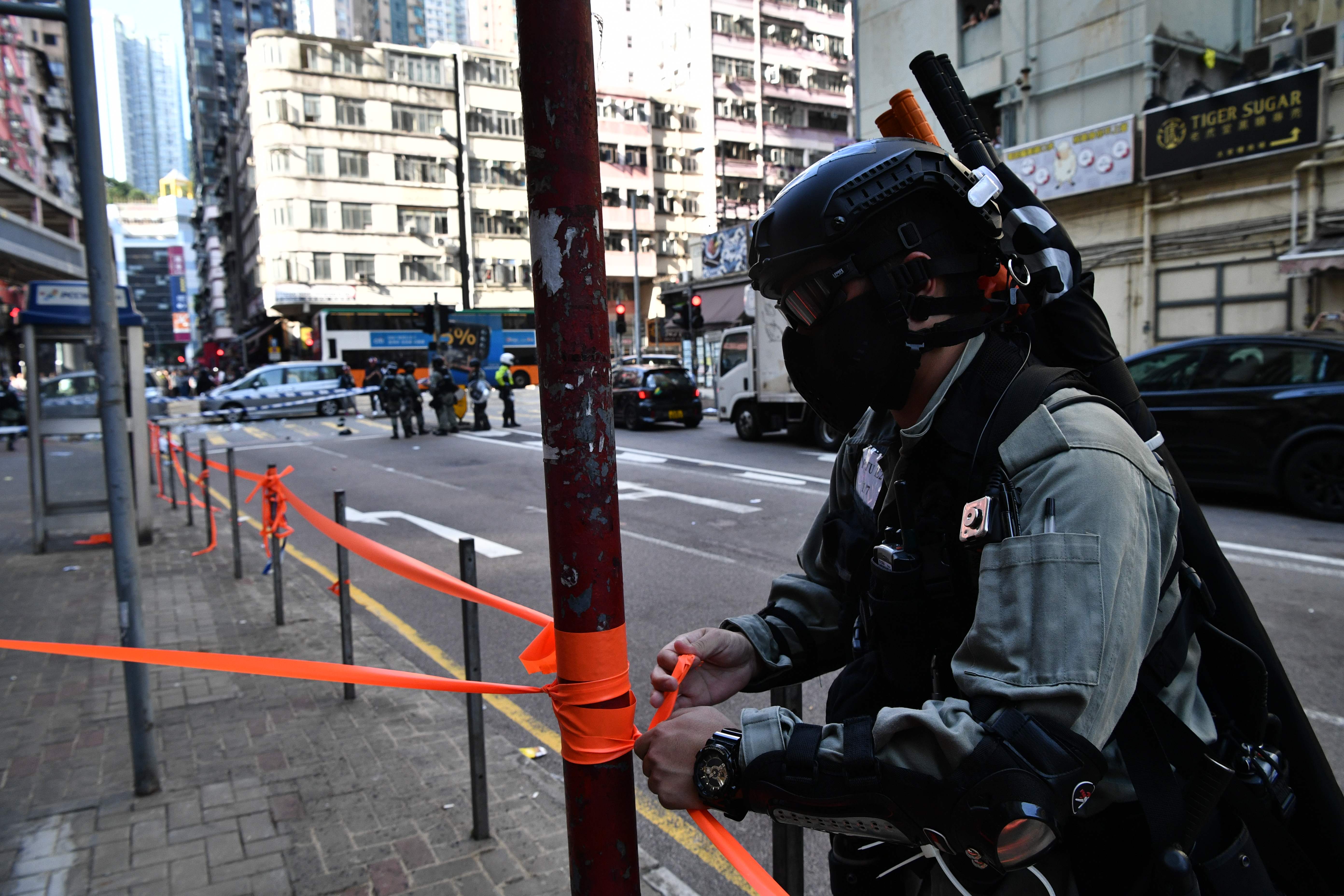 Seorang polisi Hong Kong memasang pembatas di lokasi tertembaknya seorang demonstran oleh polisi.