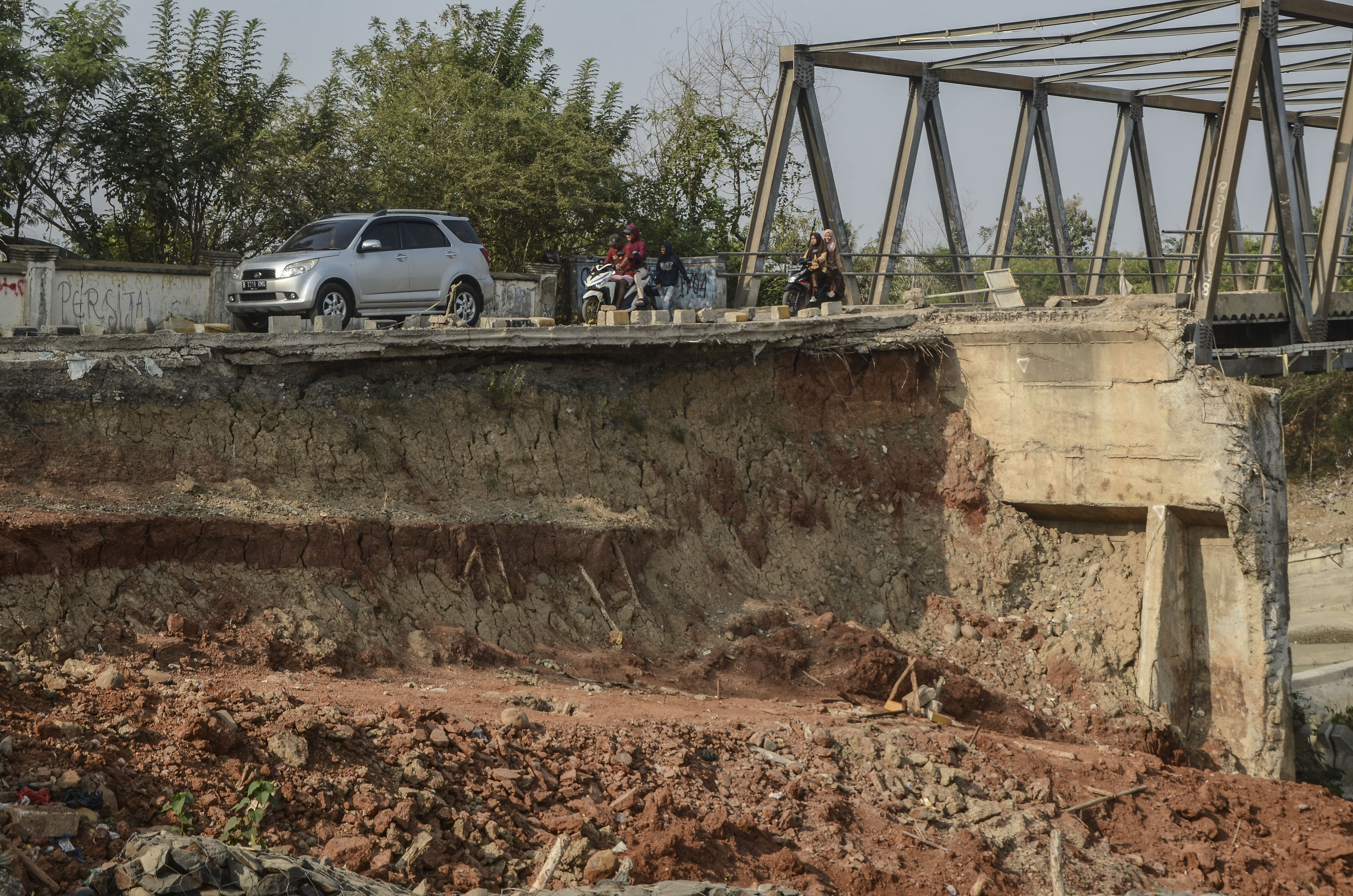 Sejumlah pengendara melintasi jalan raya Loji yang amblas di Cibarusah, Kabupaten Bekasi, Jawa Barat, Kamis (1/8/2019)