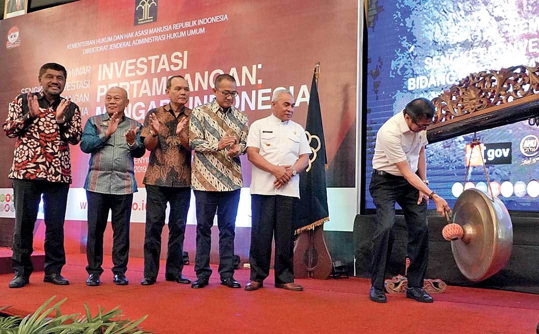 Menteri Hukum dan HAM Yasonna H Laoly memukul gong seusai berbicara dalam Seminar Sengketa Investasi Bidang Pertambangan di Indonesia.