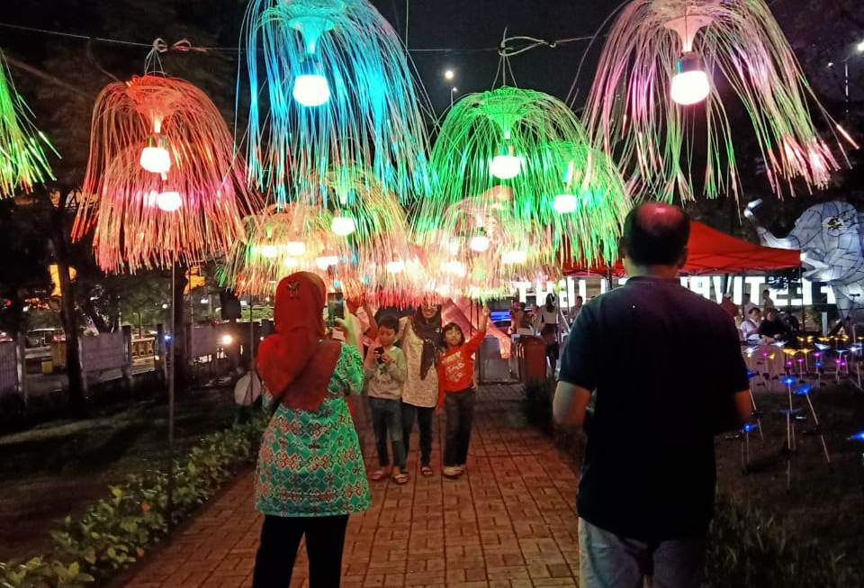 Pengunjung membawa keluarganya untuk menikmati Festival of Light Taman Waduk Ria Rio di Pulomas, Jakarta Timur. 