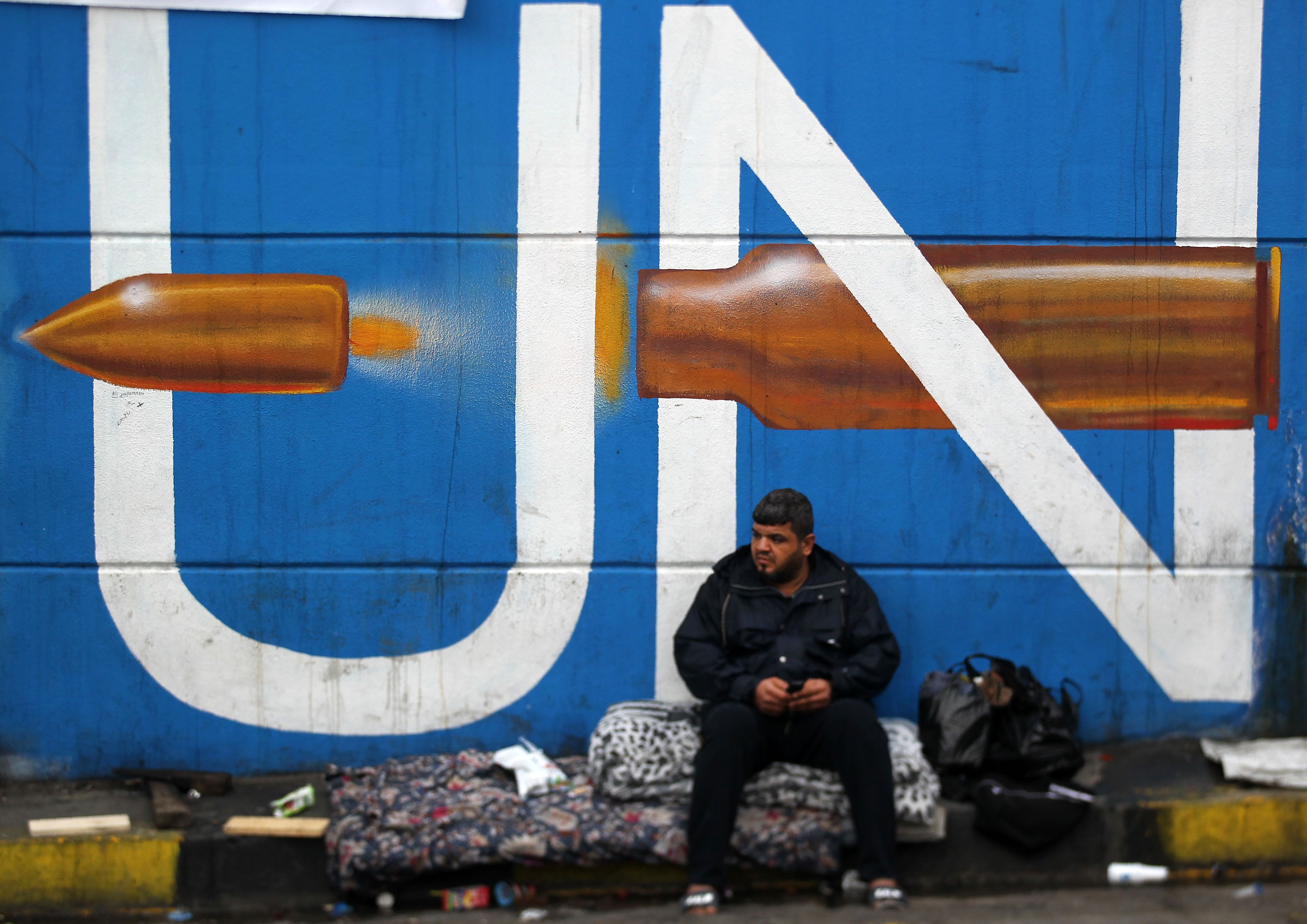 Seorang pria duduk dengan tembok gambar mural di Lapangan Tahrir, Baghdad, Irak, beberapa hari lalu.