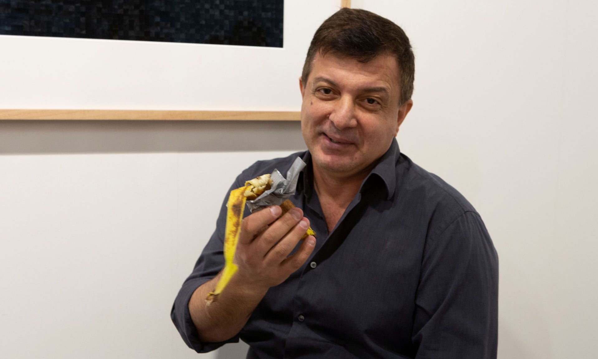 David Datuna menunjukkan sisa-sisa karya seni Komedian karya Maurizio Cattelan di Perrotin di Art Basel di Miami. 