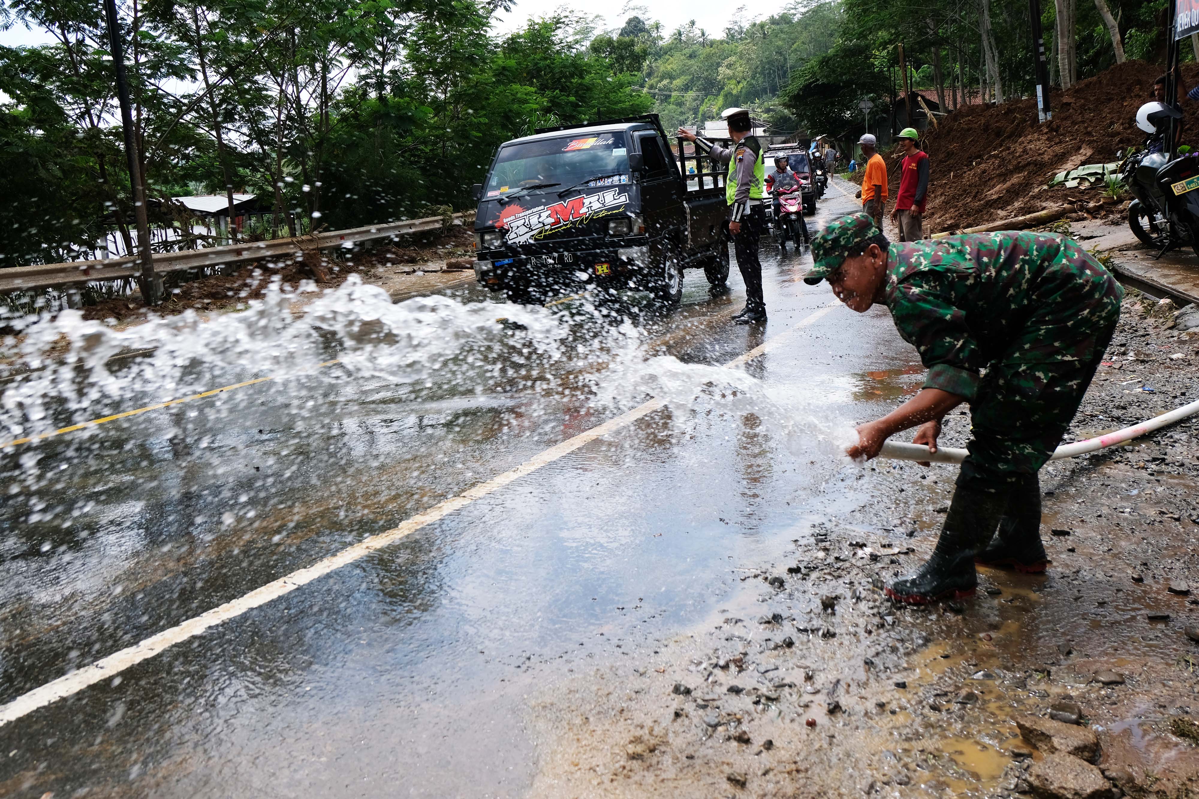 Aparat bersama warga membersihkan jalan dari timbunan tanah di jalan raya Wonosobo-Banjarnegara kecamatan Sigaluh, Banjarnegara, Jawa Tengah