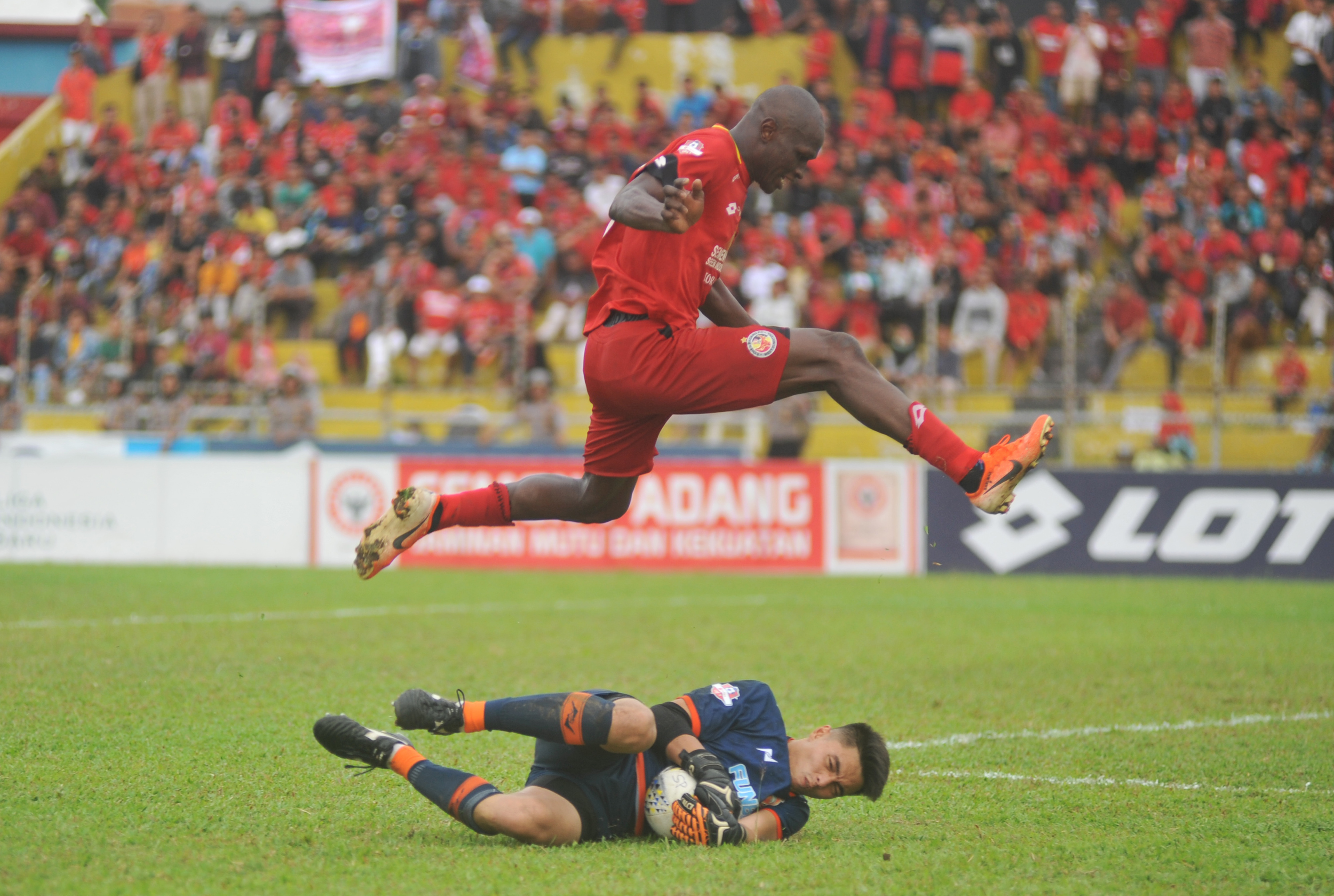 Pesepak bola Semen Padang FC, Dany Karl Max (atas) dihadang penjaga gawang Borneo FC, Gianluca P (bawah)