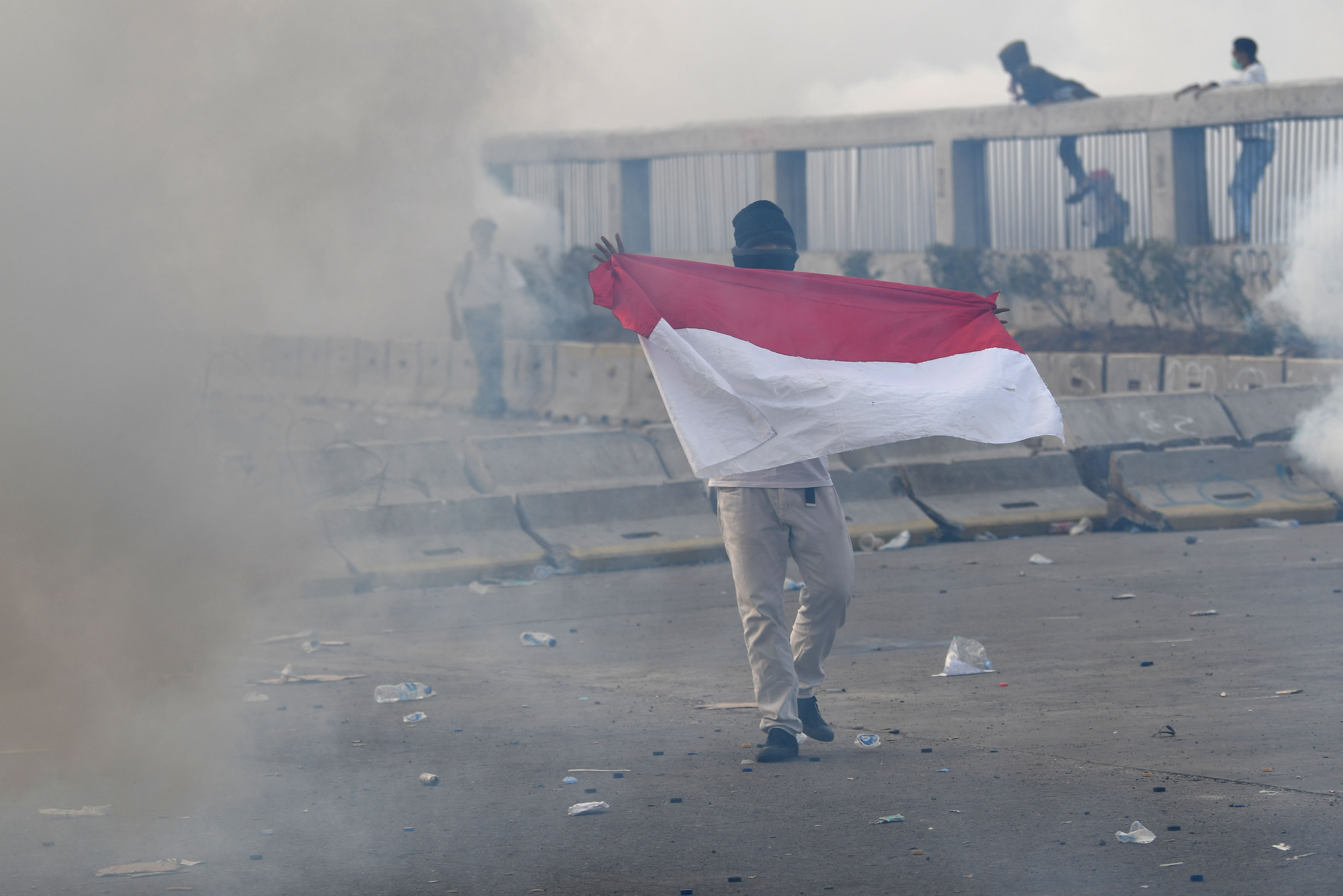 Seorang pengunjuk rasa membentangkan bendera Merah Putih saat kericuhan dalam unjuk rasa di Jalan Gatot Subroto, Jakarta, (30/9)