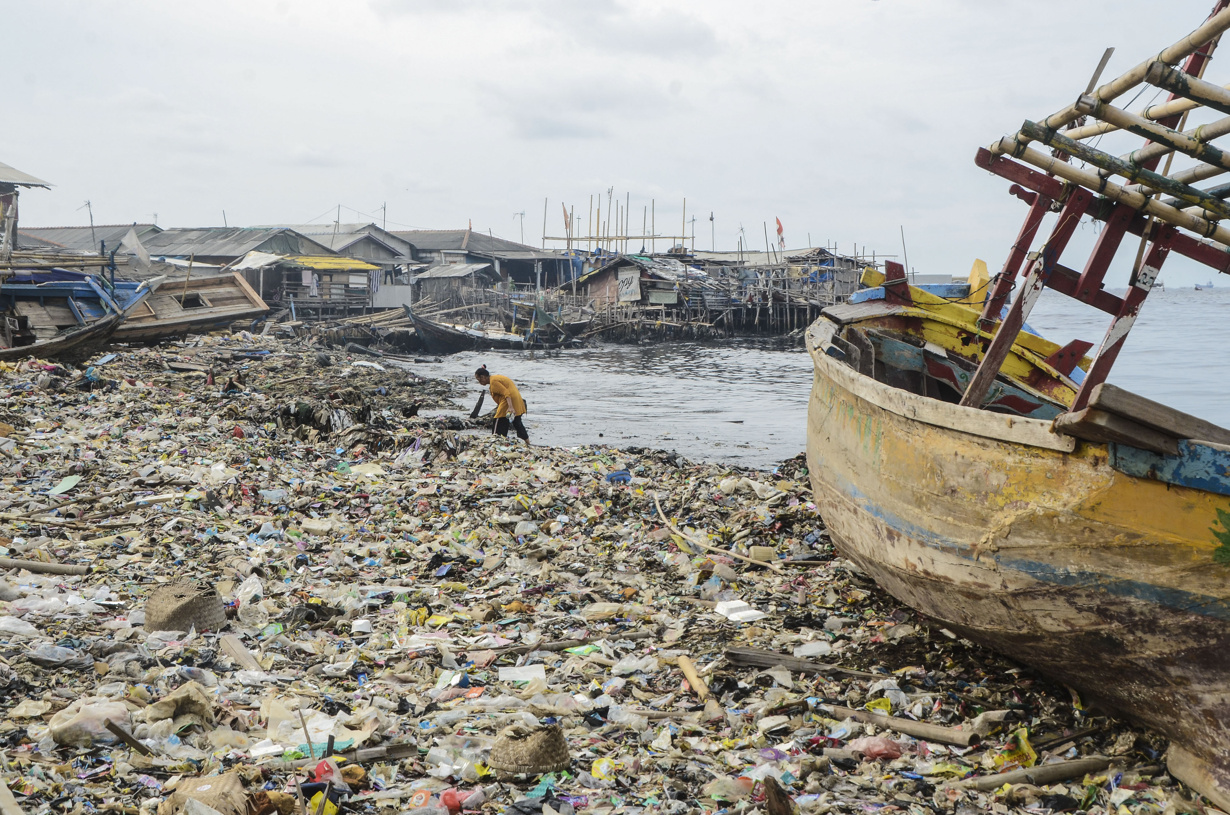 Warga beraktivitas di sekitar tumpukan sampah plastik di Pesisir laut Cilincing, Jakarta Utara, Selasa (10/12/2019).