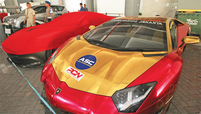 Petugas menjaga dua dari belasan mobil mewah yang diamankan di Polda Jawa Timur, Surabaya, Jawa Timur, kemarin.