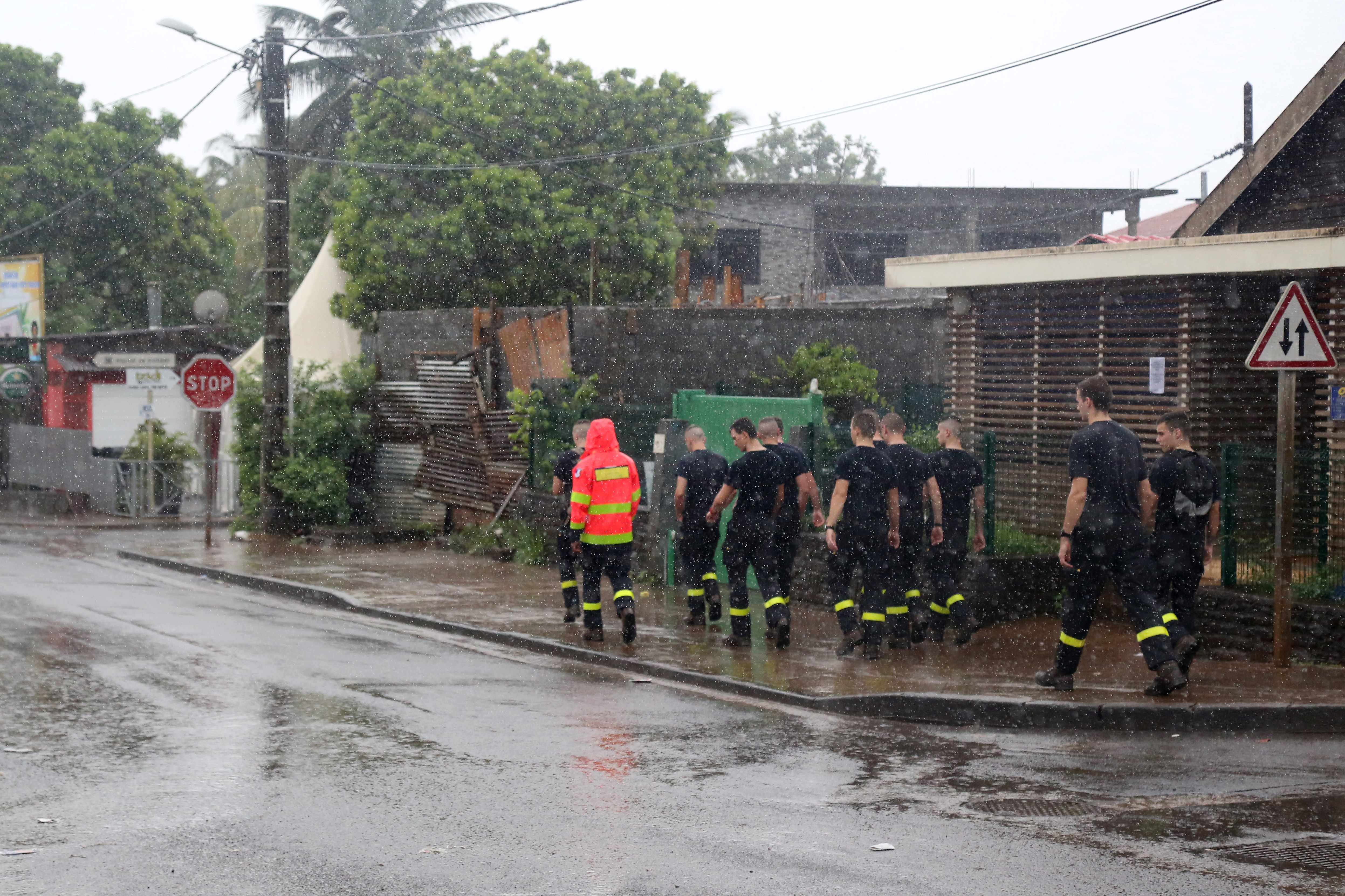 Petugas pemadam kebakaran berjalan di sepanjang jalan nasional saat hujan turun di Combani di pulau Mayotte di Prancis.