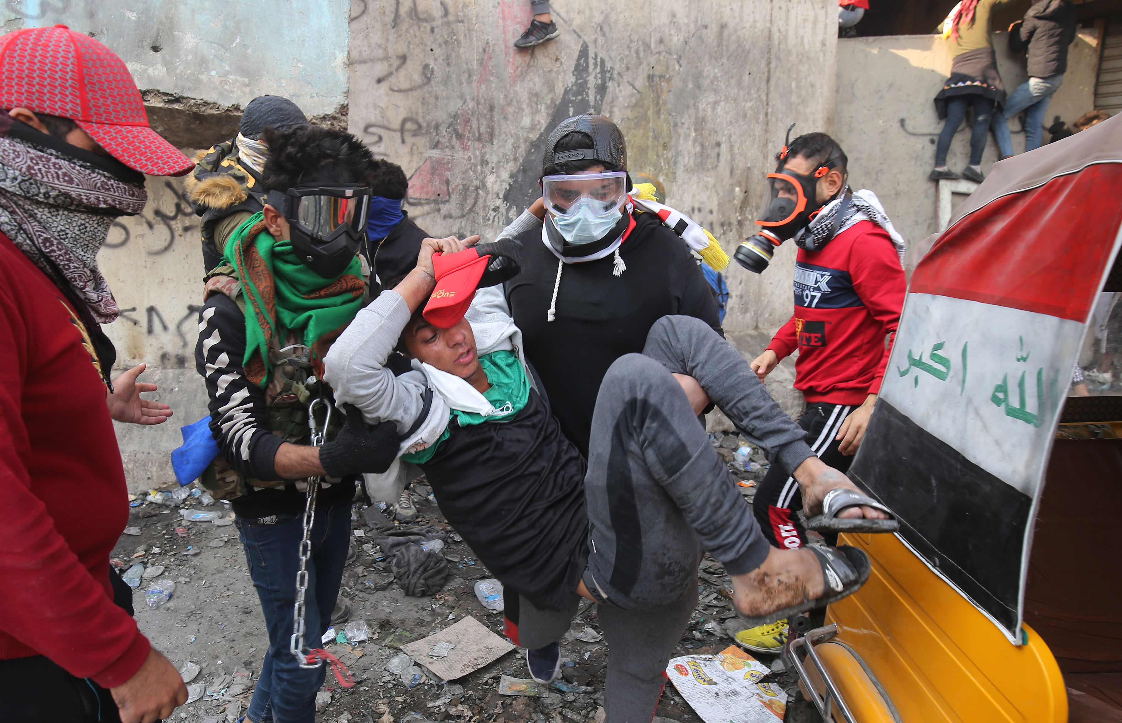 Demonstran Irak membantu rekan mereka yang terluka dalam bentrok dengan pasukan keamanan.