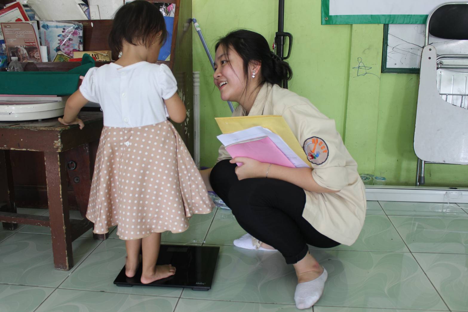 Mahasiswa FK Unika Atma Jaya yang tergabung di komunitas Hazard Analysis and Critical Control Point sedang mengukur berat badan anak.
