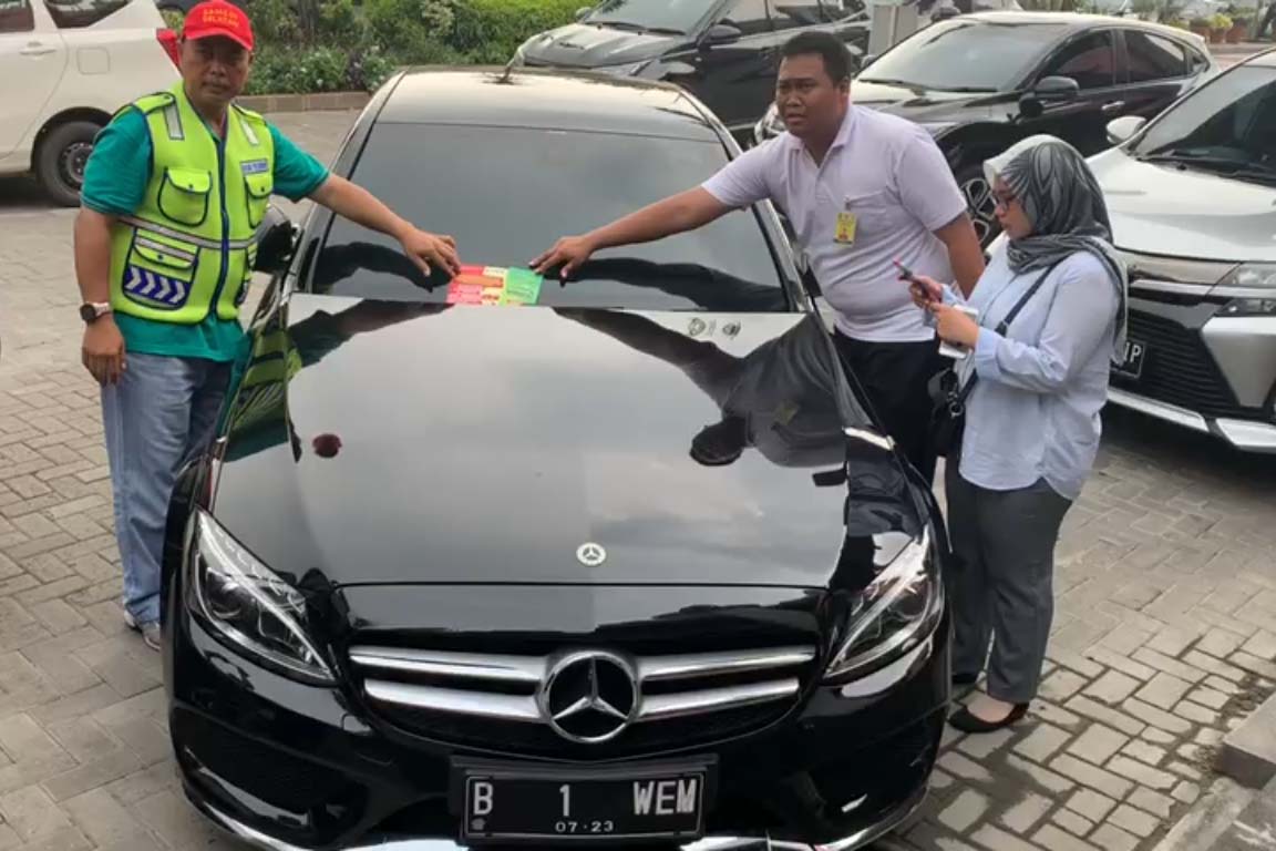 Petugas menempeli stiker di mobil yang menunggak pajak. 