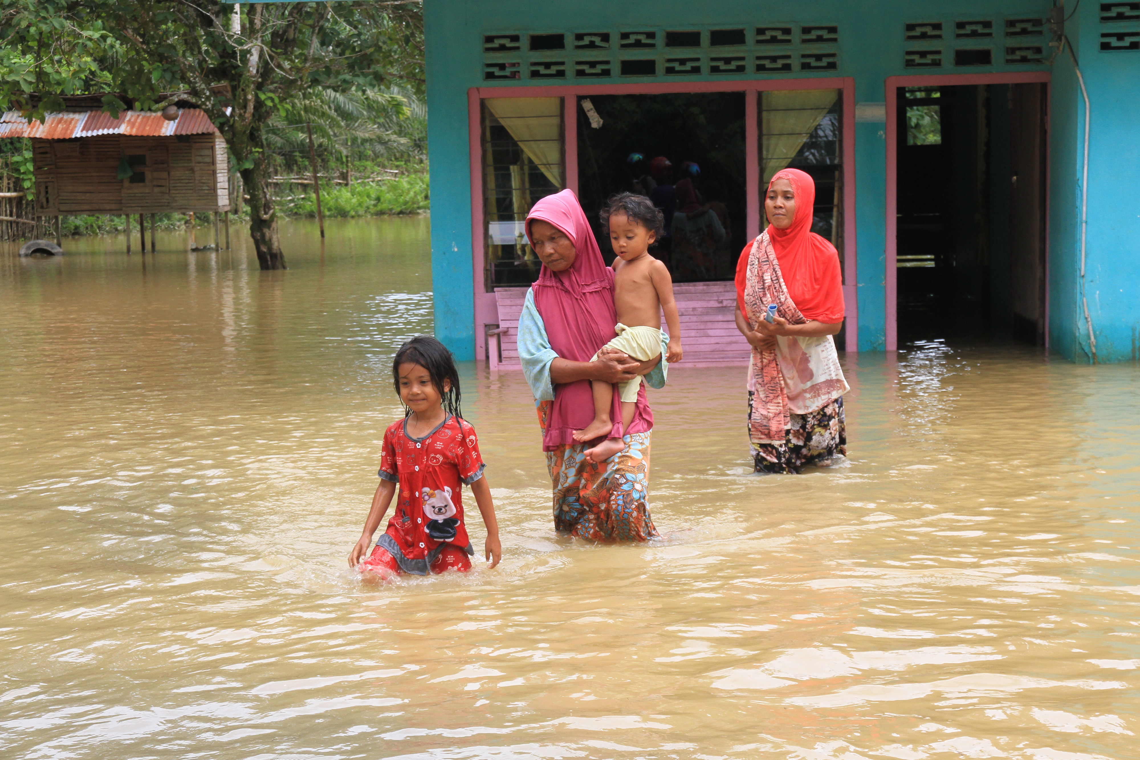  Sejumlah warga melintas di depan rumahnya yang terendam banjir di Desa Marek, Kecamatan Kaway XVI, Aceh Barat, Aceh, Senin (2/12/2019)