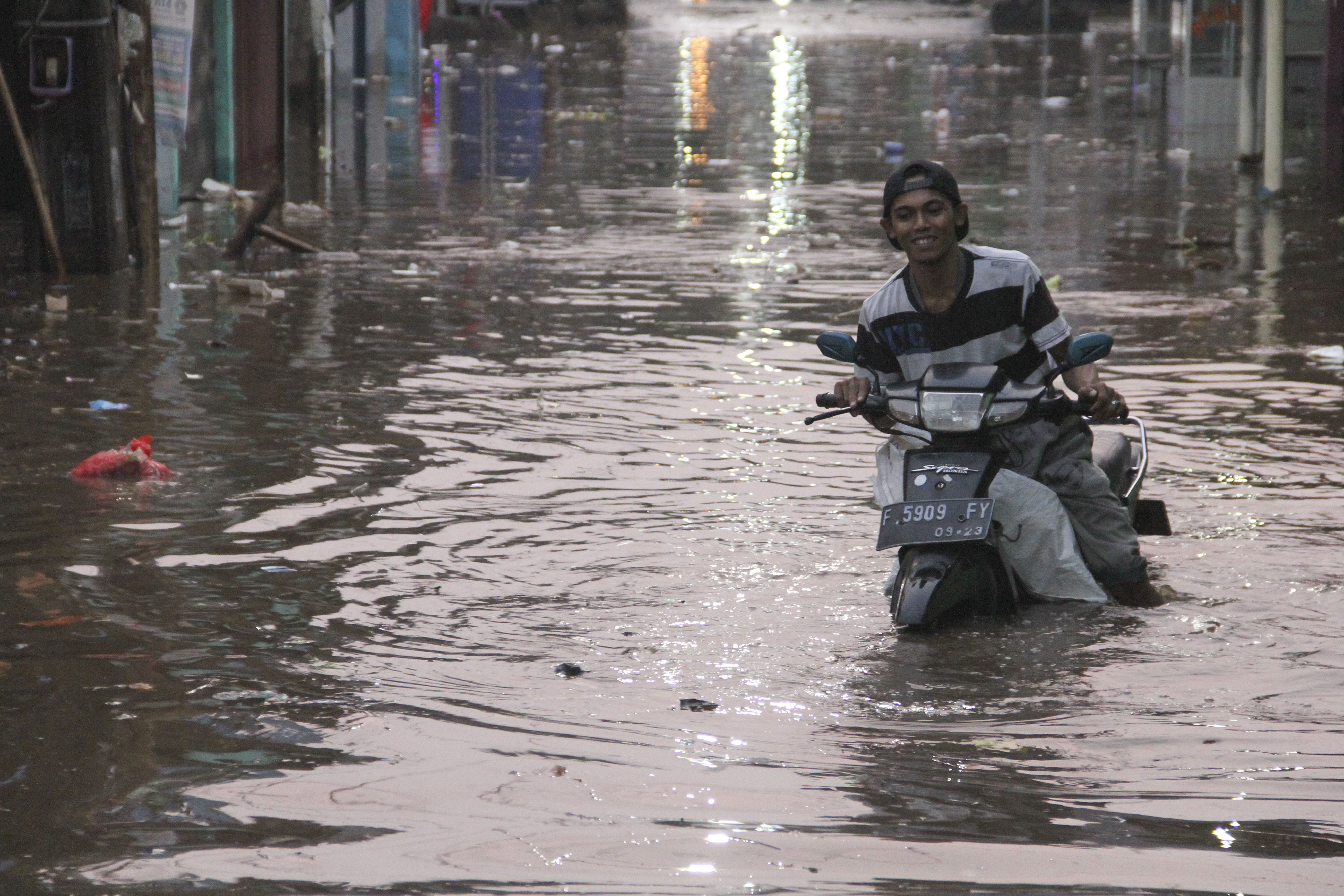Seorang pengendara motor yang mogok karena banjir di Depok, Jawa Barat, Kamis (15/8/2019).
