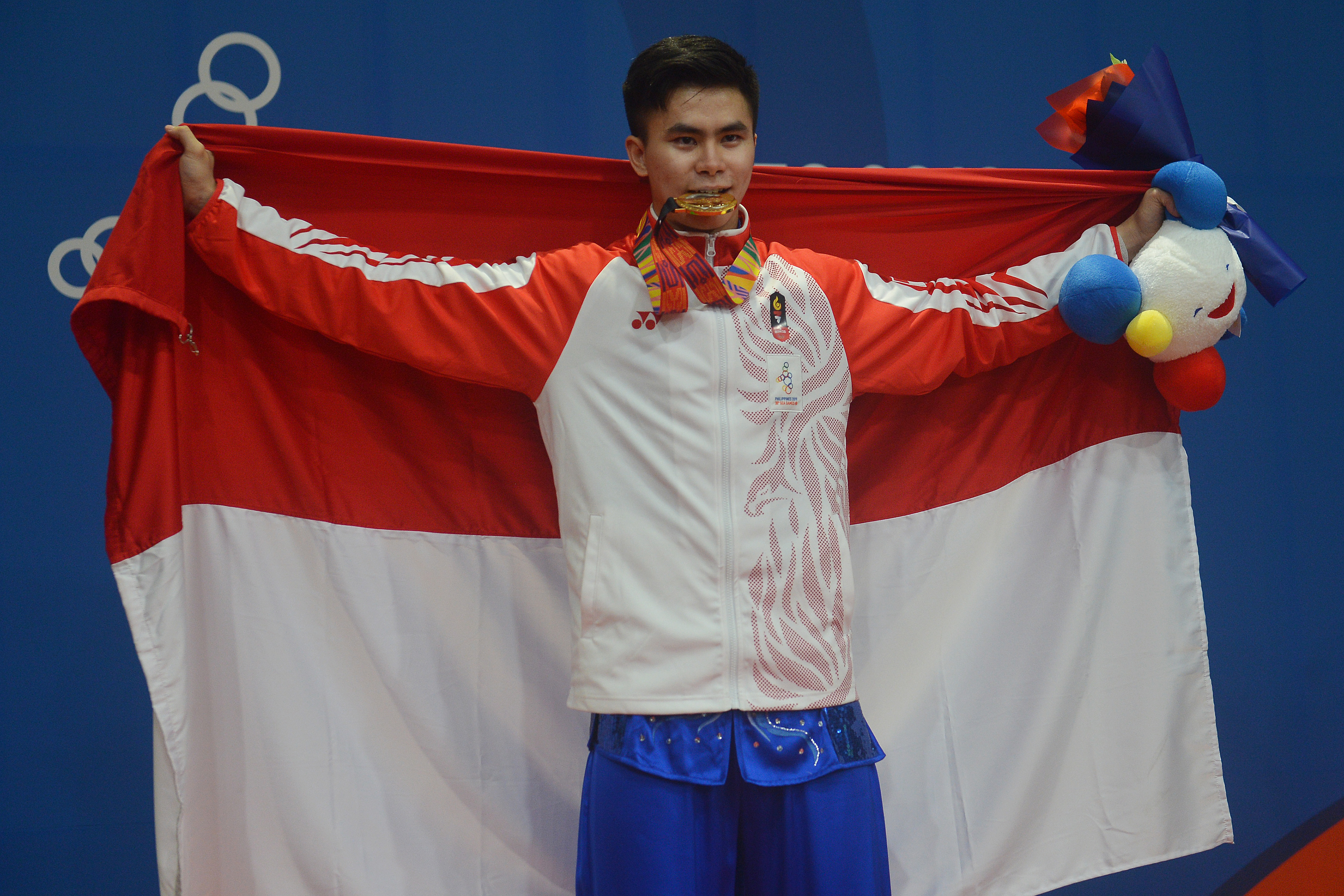  Atlet wushu Indonesia Edgar Xavier Marvelo menggigit medali setelah memenangi nomor Wushu Gunshu Putra SEA Games ke-30
