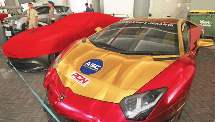 Petugas menjaga dua dari belasan mobil mewah yang diamankan di Polda Jawa Timur, Surabaya, Jawa Timur, kemarin.