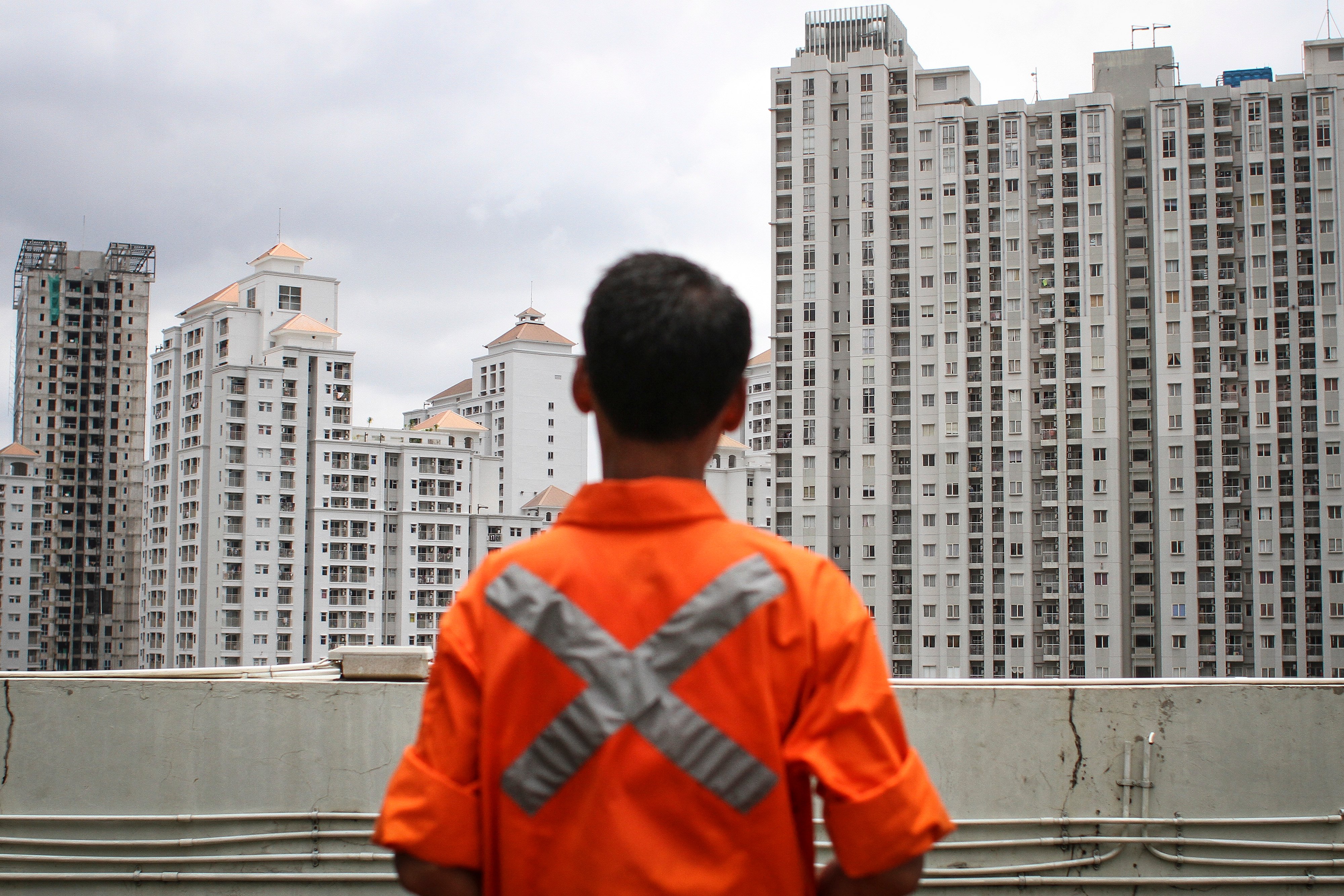 Aktivitas petugas taman dengan latar belakang deretan apartemen di kawasan Jakarta Barat.