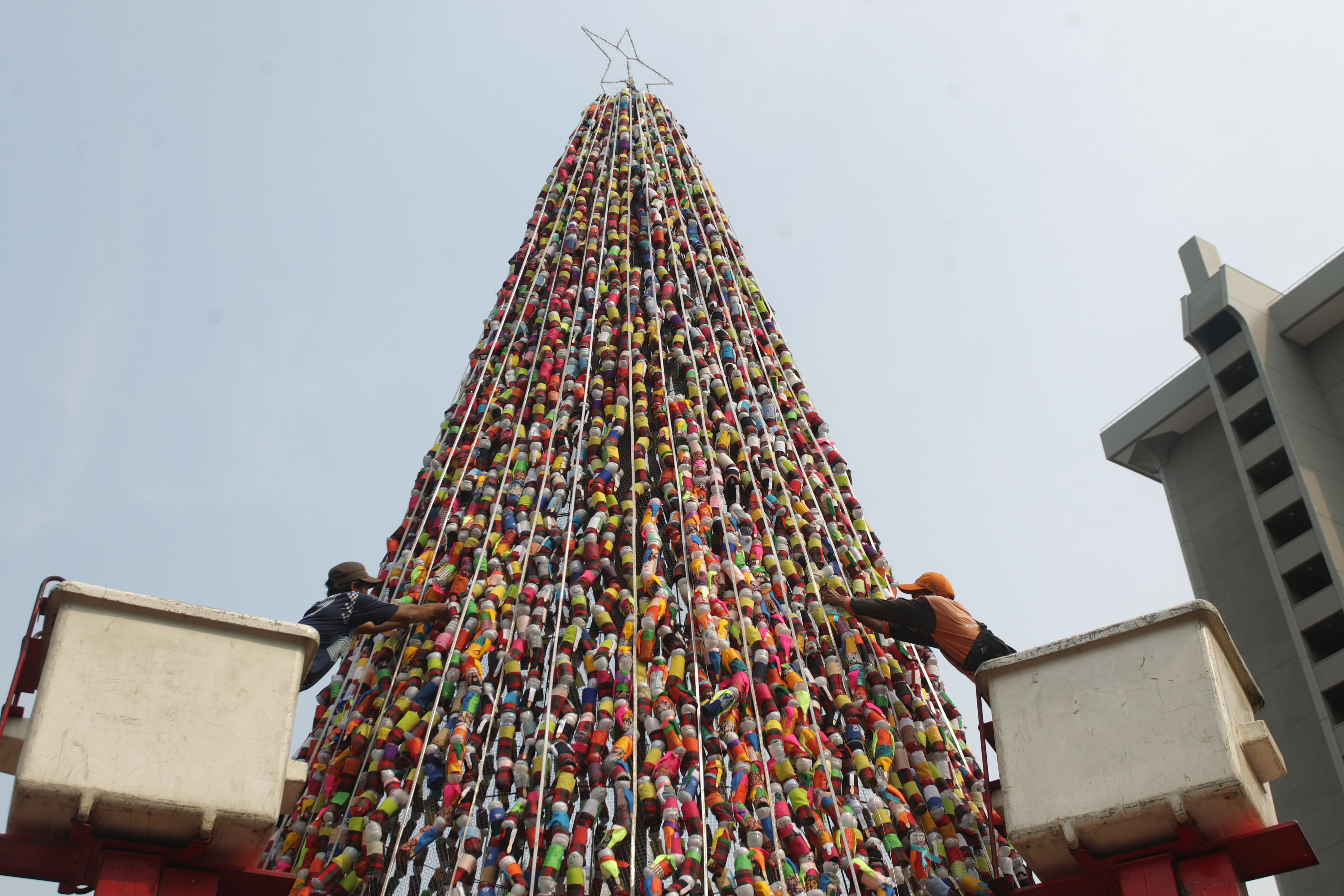  Petugas Penanganan Prasaran dan Sarana Umum menata pohon Natal miniatur ondel-ondel yang terbuat dari botol minuman bekas di Jalan Thamrin