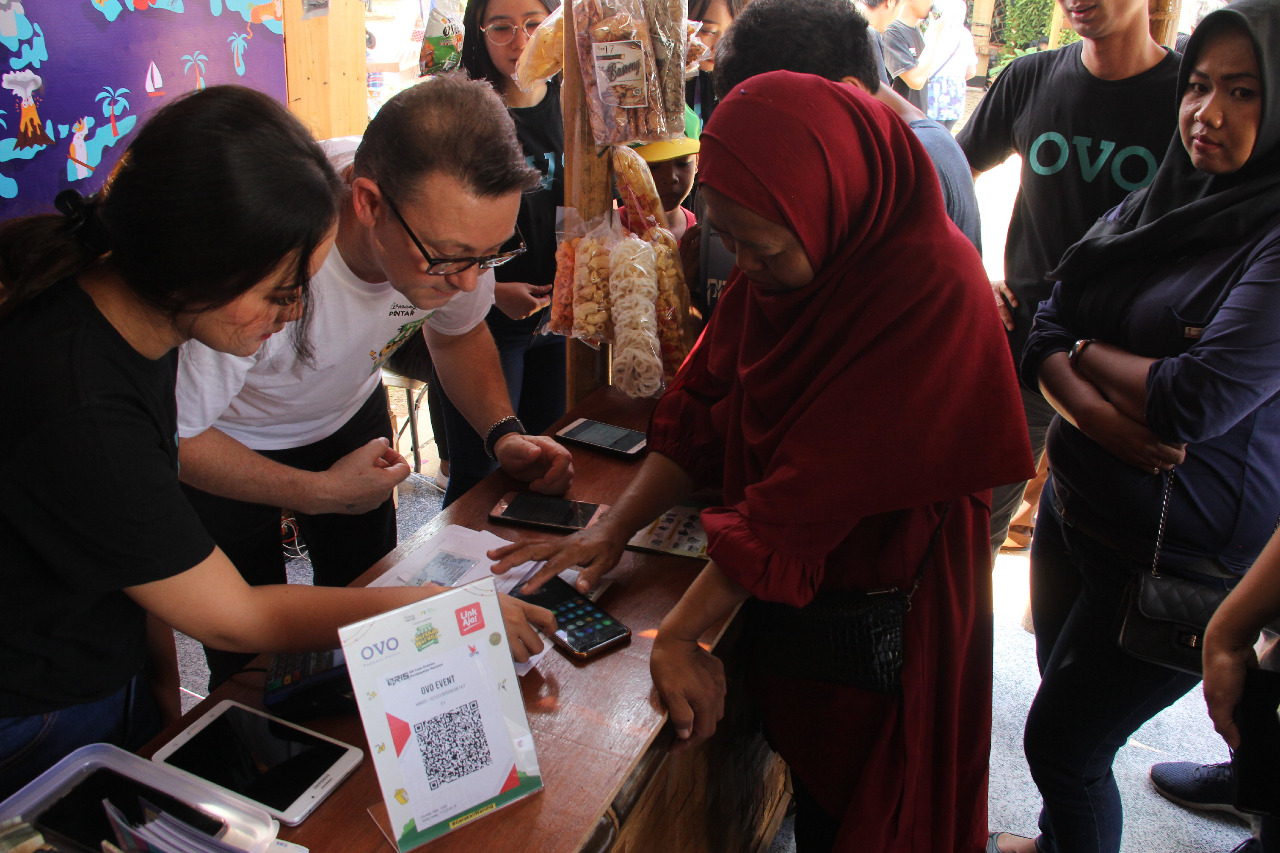 CEO OVO Jason Thompson memberikan pengarahan kepada warga yang hendak berbelanja cara menggunakan QRIS melalui aplikasi OVO.