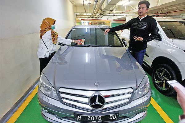 Petugas menempelkan stiker peringatan pada kendaraan yang menunggak pajak saat razia pajak di parkiran Pacific Place, Jakarta, Minggu (22/12