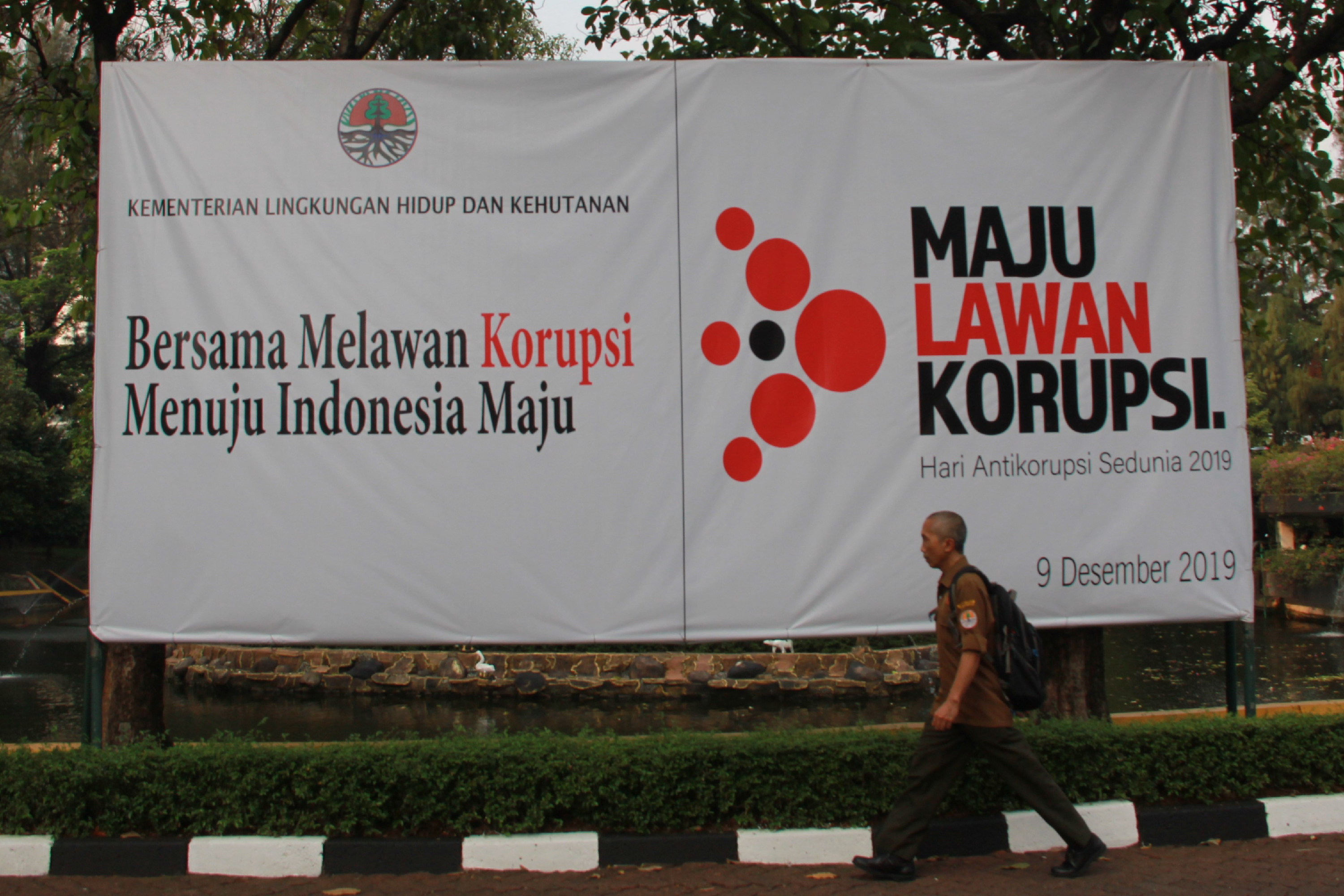 Pegawai Kementrian Lingkungan Hidup dan Kehutanan berjalan melewati spanduk bertuliskan 