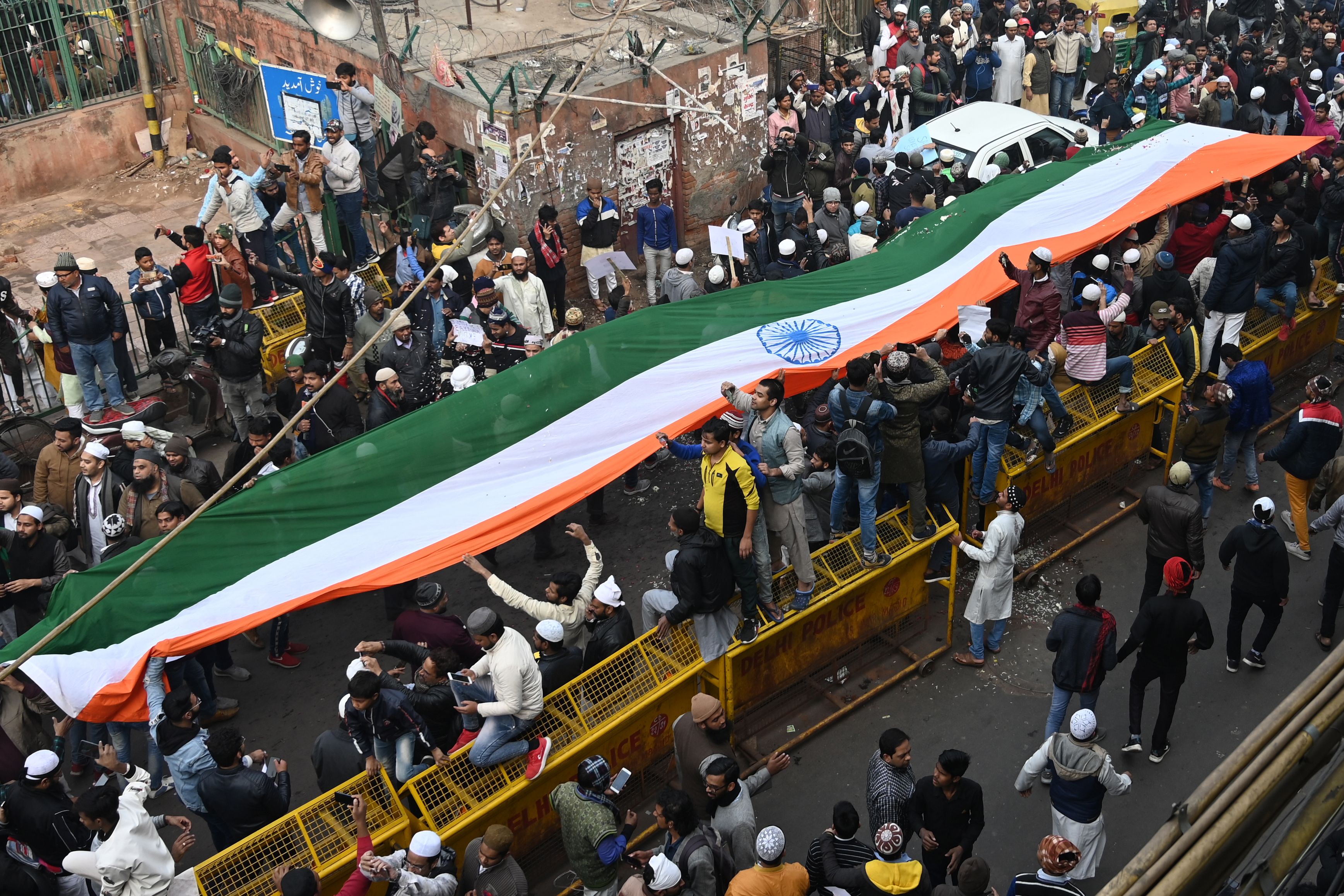Para pengunjuk rasa membentangkan bendera panjang di depan masjid Jama di New Delhi, India.