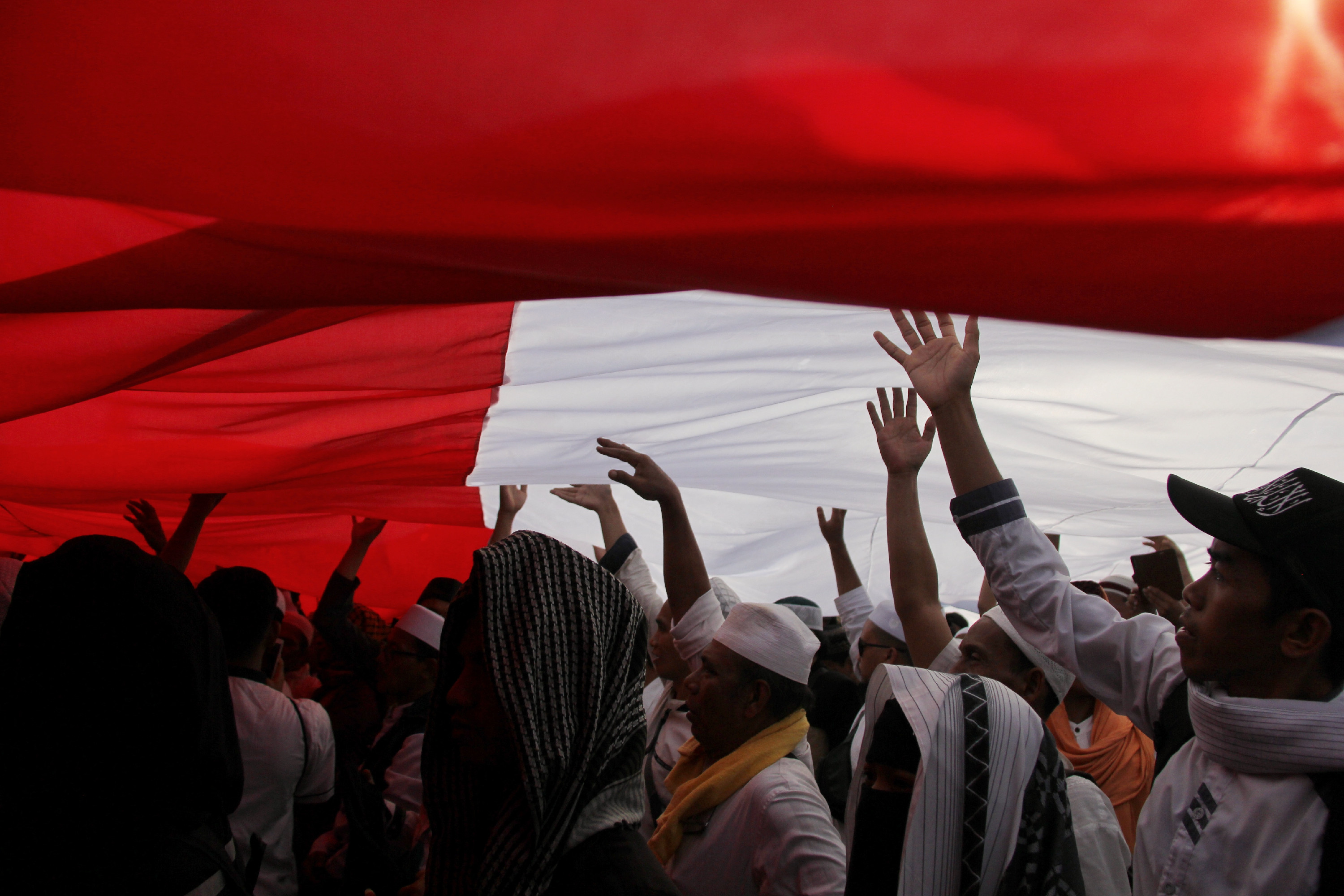  Peserta aksi membentangkan bendera Merah Putih di tengah-tengah masa yang tergabung dalam reuni 212 di kawasan Monas, Jakarta Pusat, Senin 