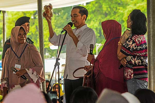 Presiden Joko Widodo menunjukkan keripik hasil produksi usaha mikro kecil menengah (UMKM) di Alun-alun Cilegon, Banten, Jumat (6/11/2019).