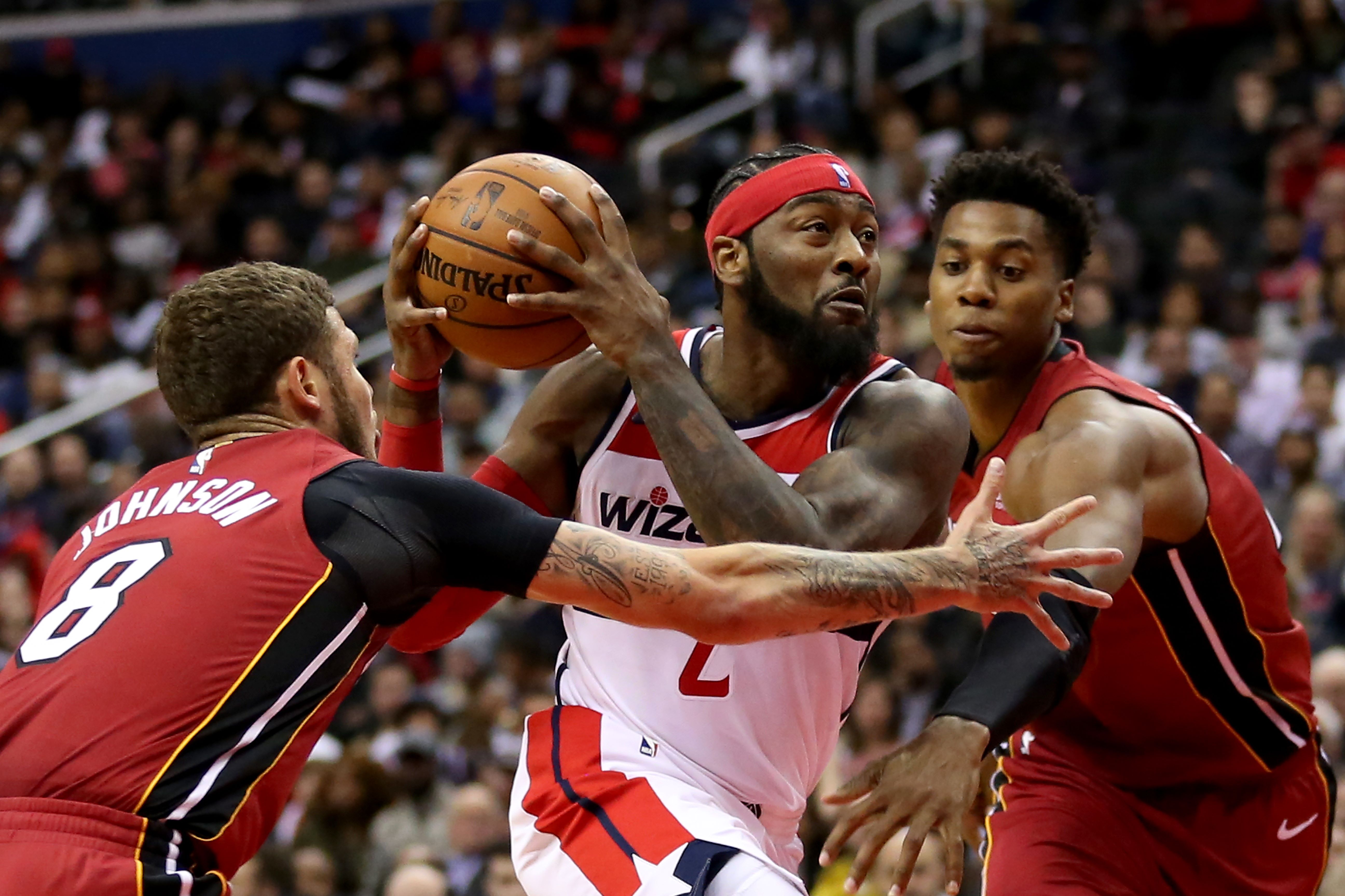  John Wall dari Washinton Wizards (tengah) menerjang rintangan Tyler Johnson (kiri) dan Hassan Whiteside (kanan) dari Miami Heat