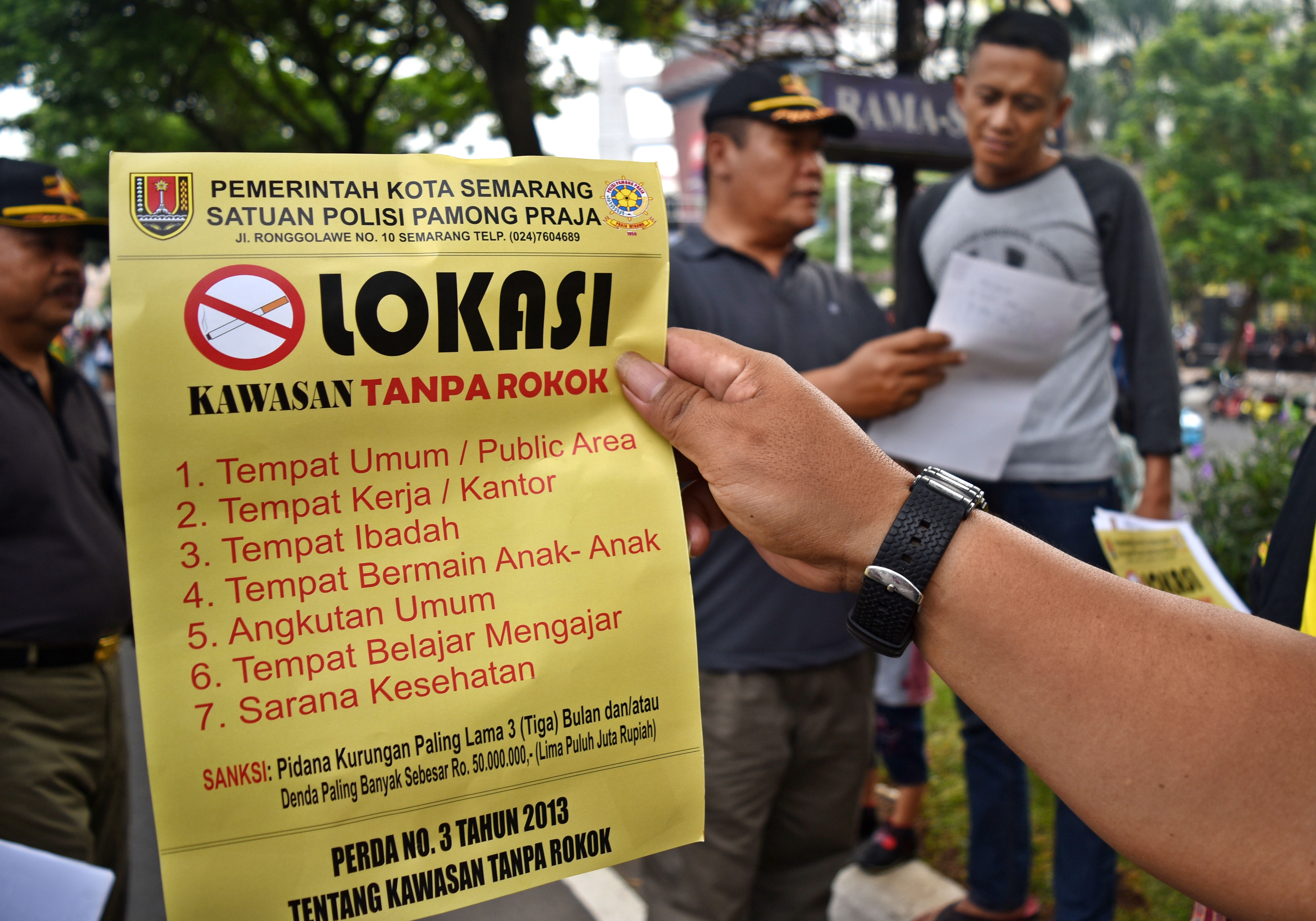 Petugas Satpol PP memberikan surat peringatan kepada warga yang merokok di tempat umum saat razia di area Hari Bebas Kendaraan Bermotor 