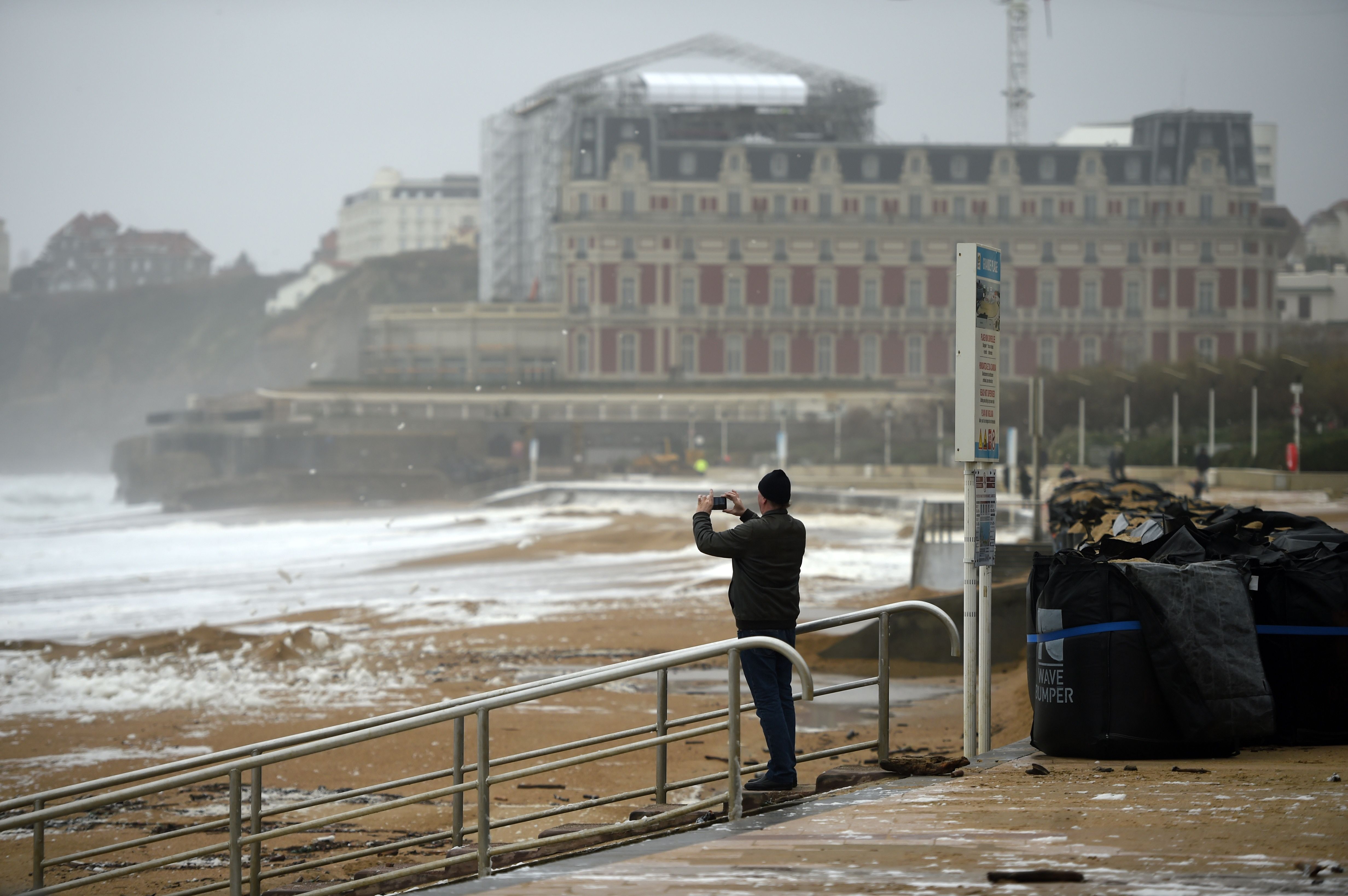 Seorang pria mengambil gambar saat badai di Grande Plage di Biarritz, Prancis.
