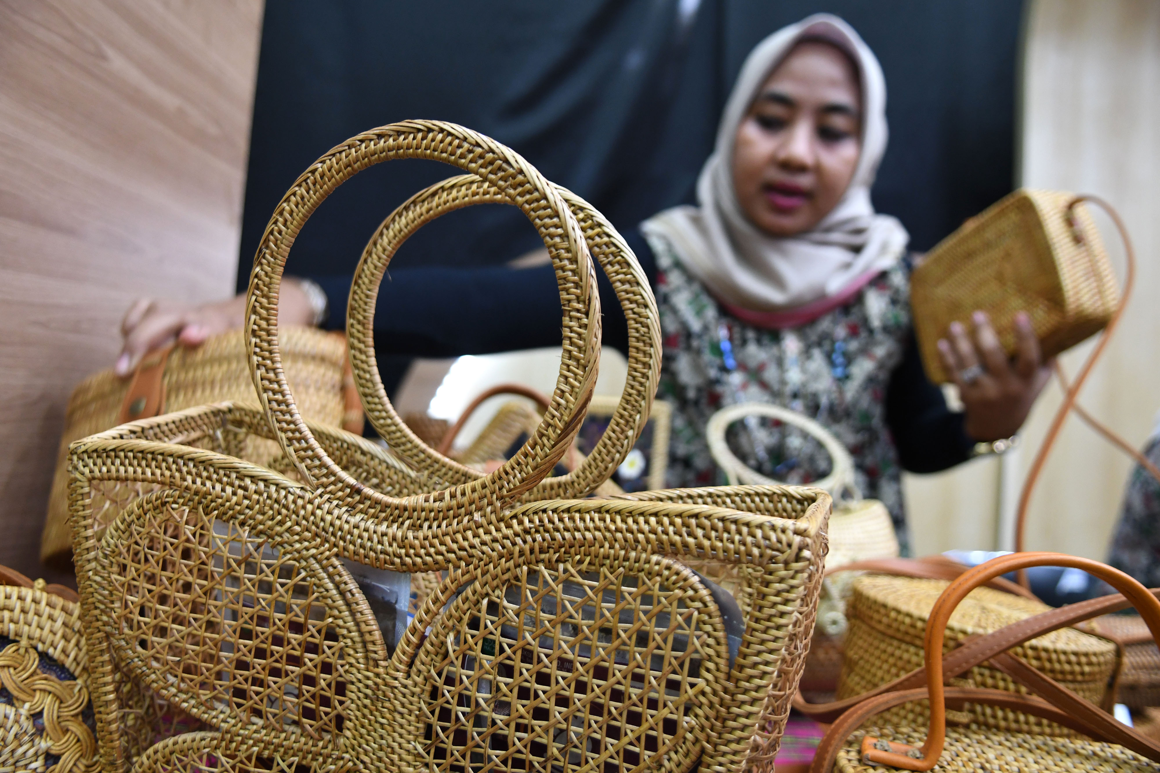 Perajin merapikan tas anyaman rotan buatannya yang dipamerkan dalam salah satu pameran di Jakarta
