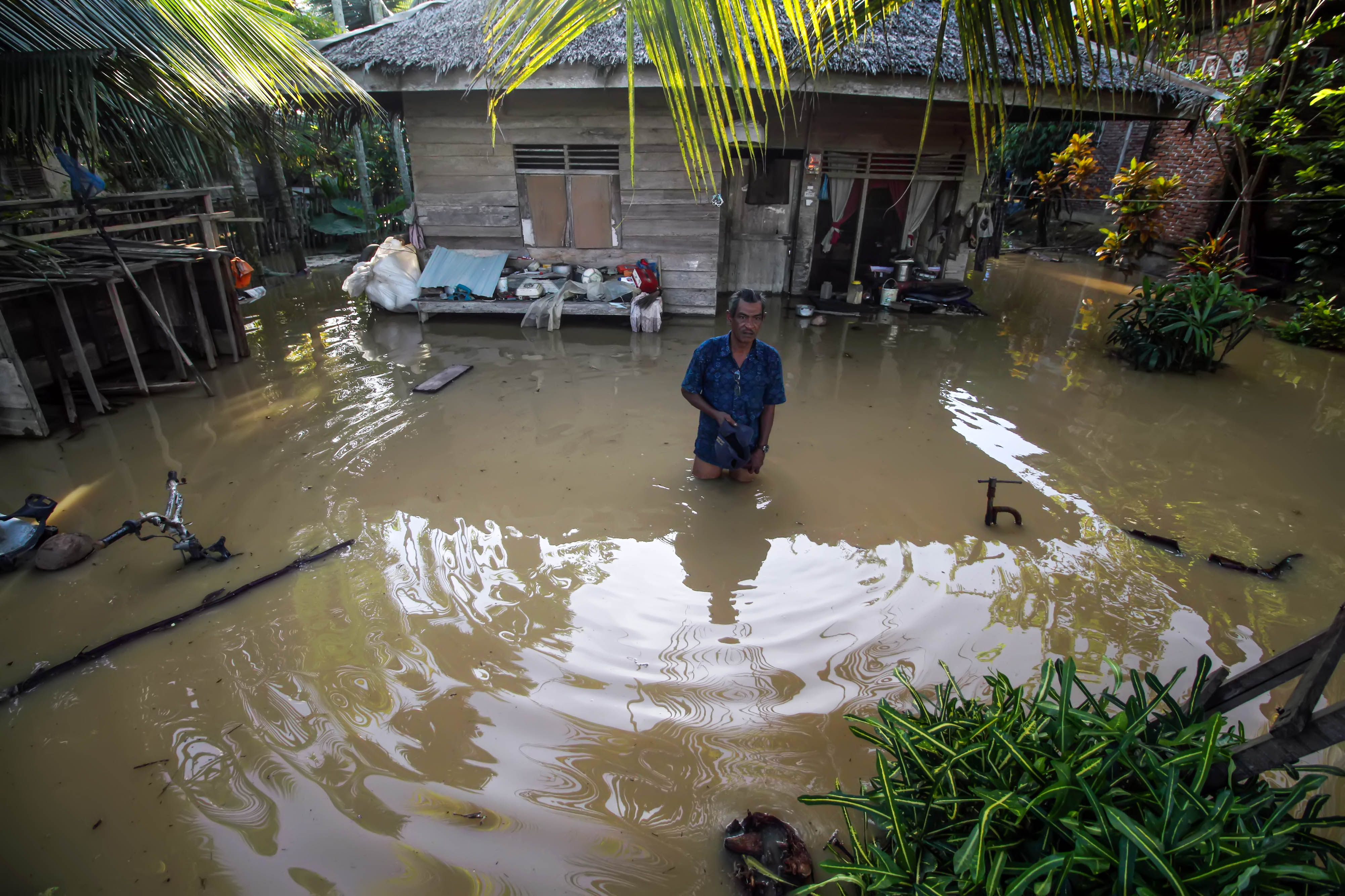 Warga berdiri di depan rumahnya terendam banjir di Desa Hasan Kareueng, Kecamatan Blang Mangat, Lhokseumawe, Aceh, Senin (16/12/2019)