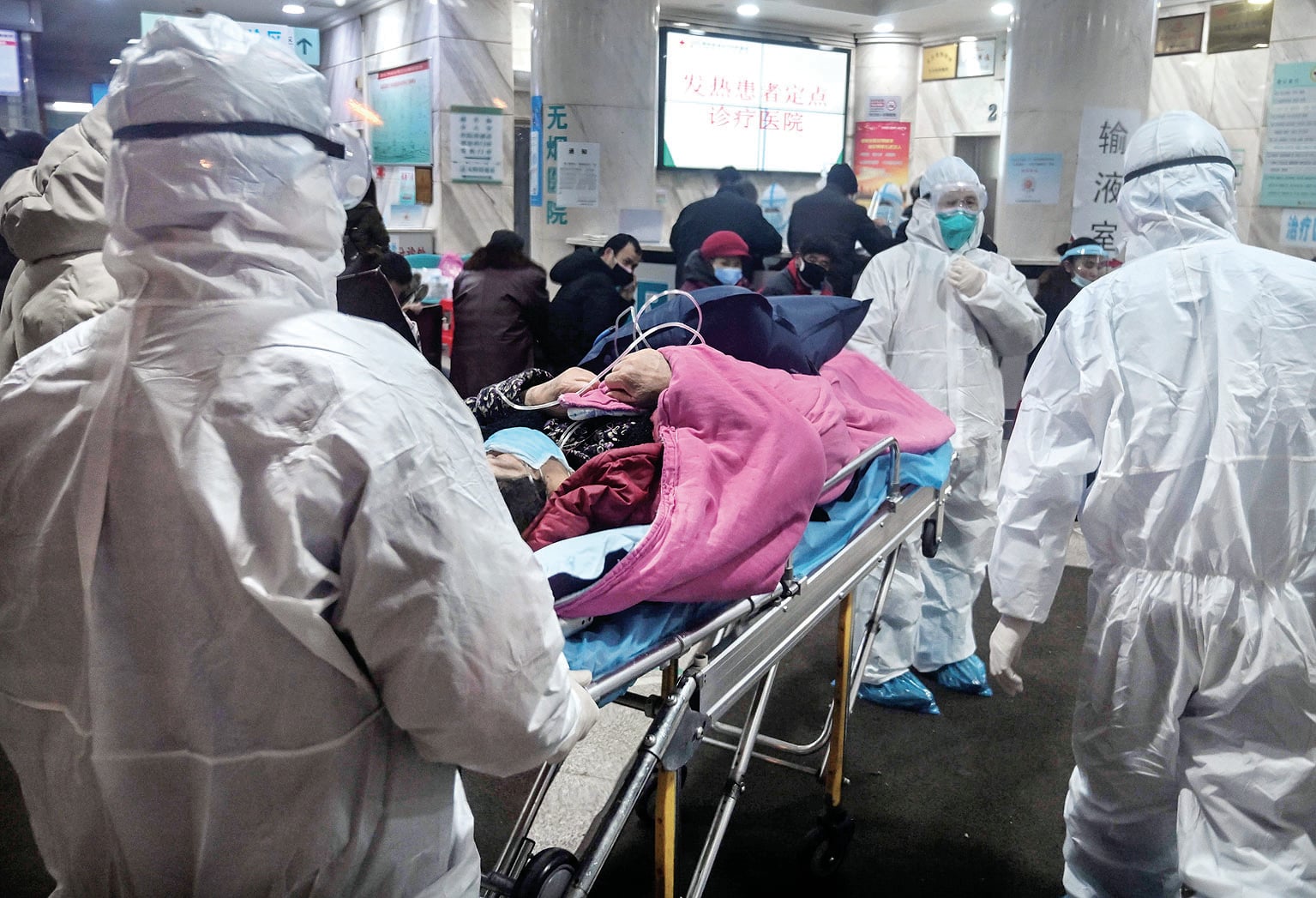 Petugas medis dengan mengenakan baju pelindung untuk mengantisipasi virus korona membawa pasien yang diduga terserang virus tersebut.