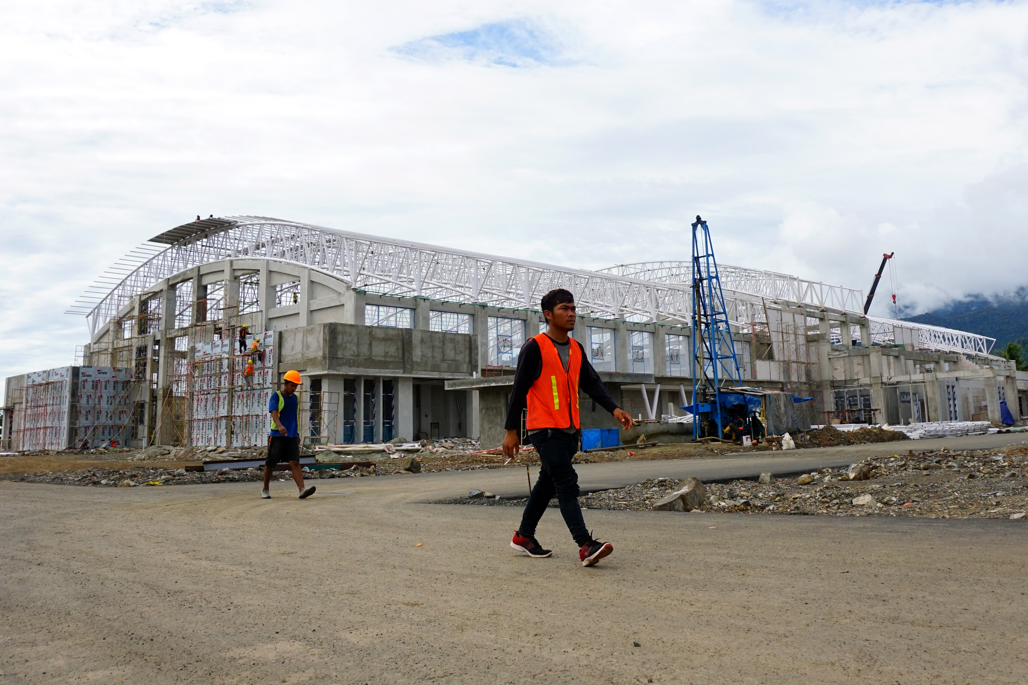Pekerja melintasi kawasan proyek pembangunan Venue Hockey dan Kriket di Doyo Baru, Kabupaten Jayapura, Papua.