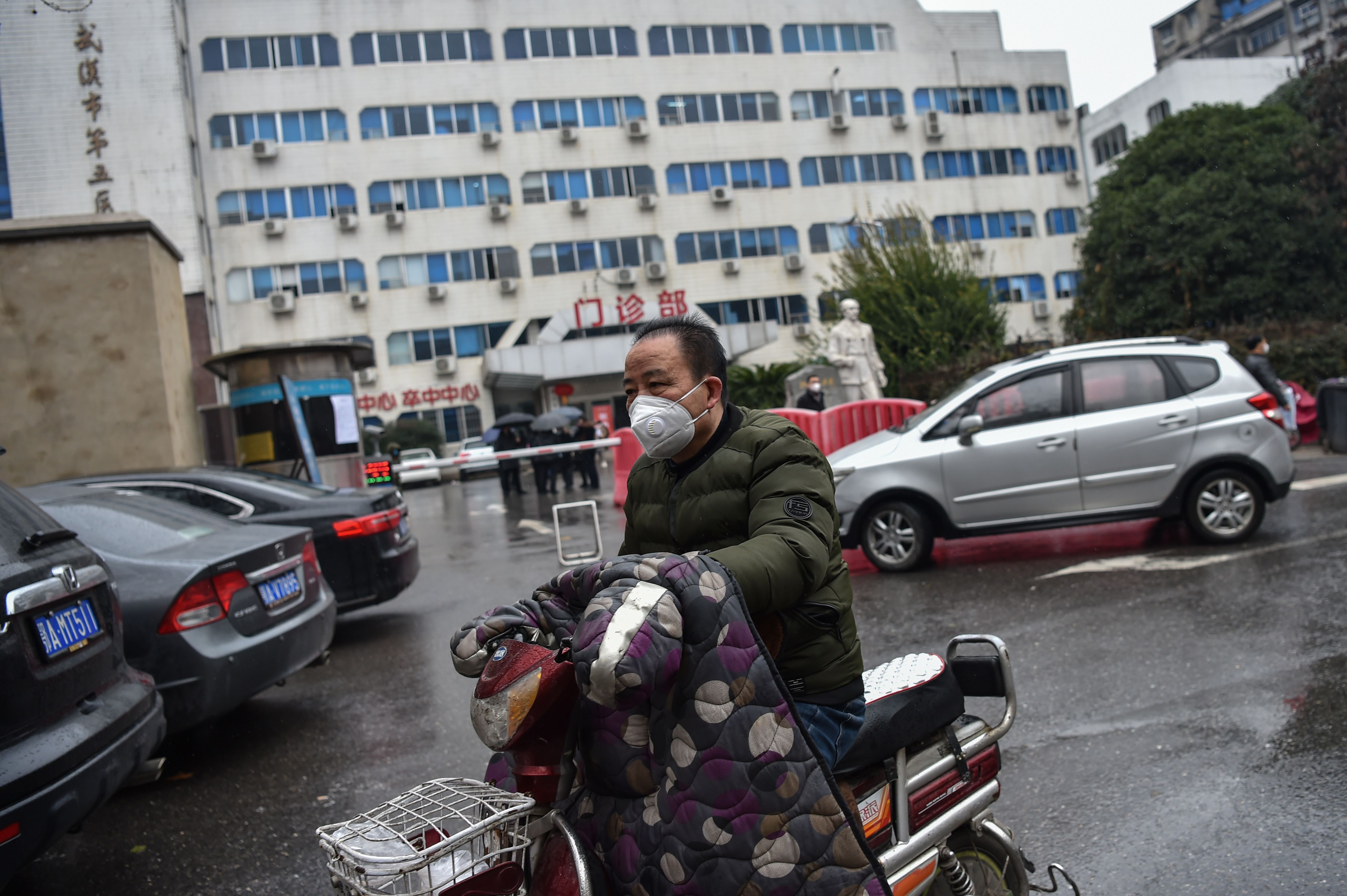  Seorang pengendara menggunakan masker dan melewati  Wuhan Fifth Hospital di Kota Wuhan, Hubei, Tiongkok.