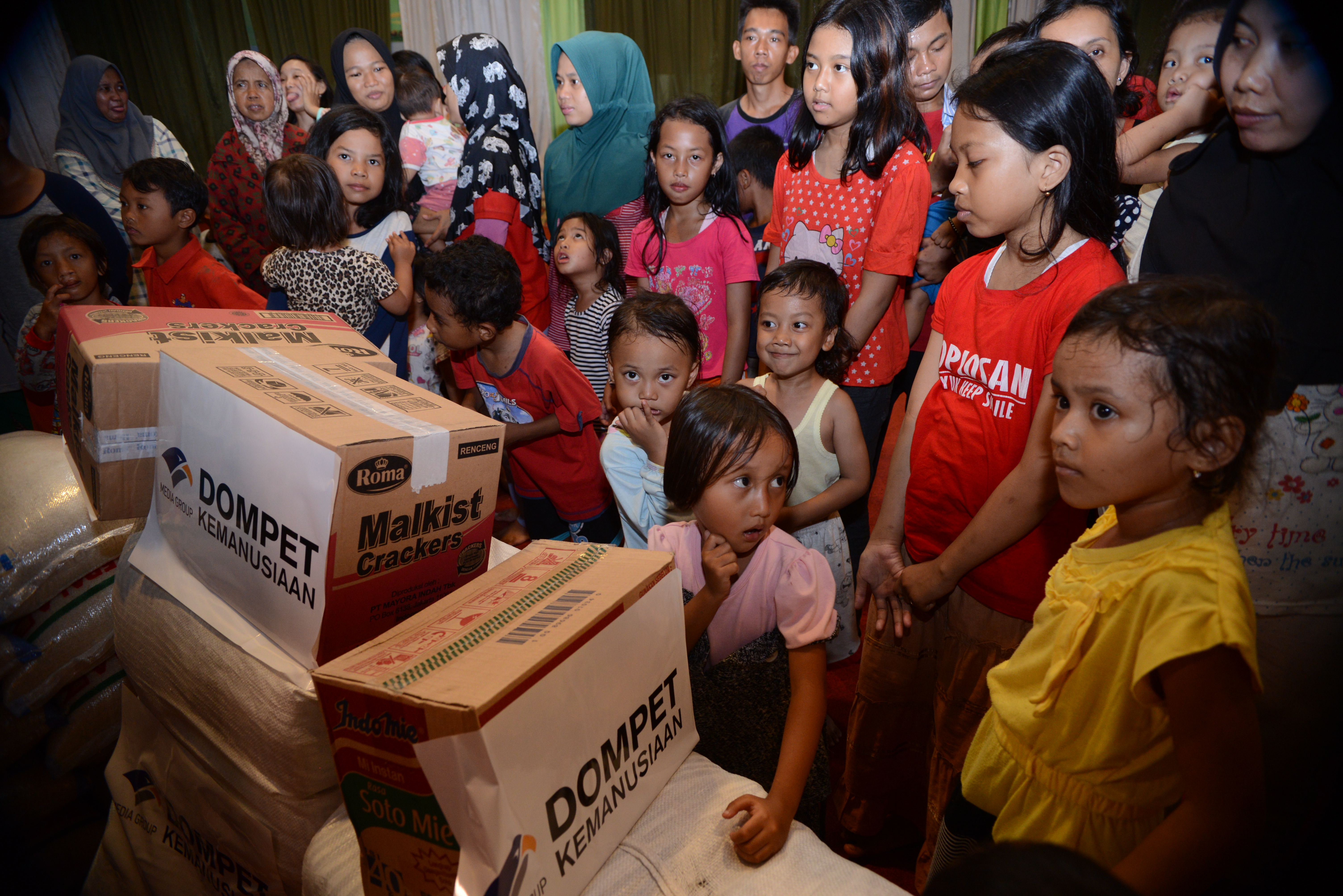 Anak-anak berdiri di dekat paket bantuan Media Group di komplek wisma Siti Maryam, Kedoya Utara, Jakarta, Jumat (3/1/2020).