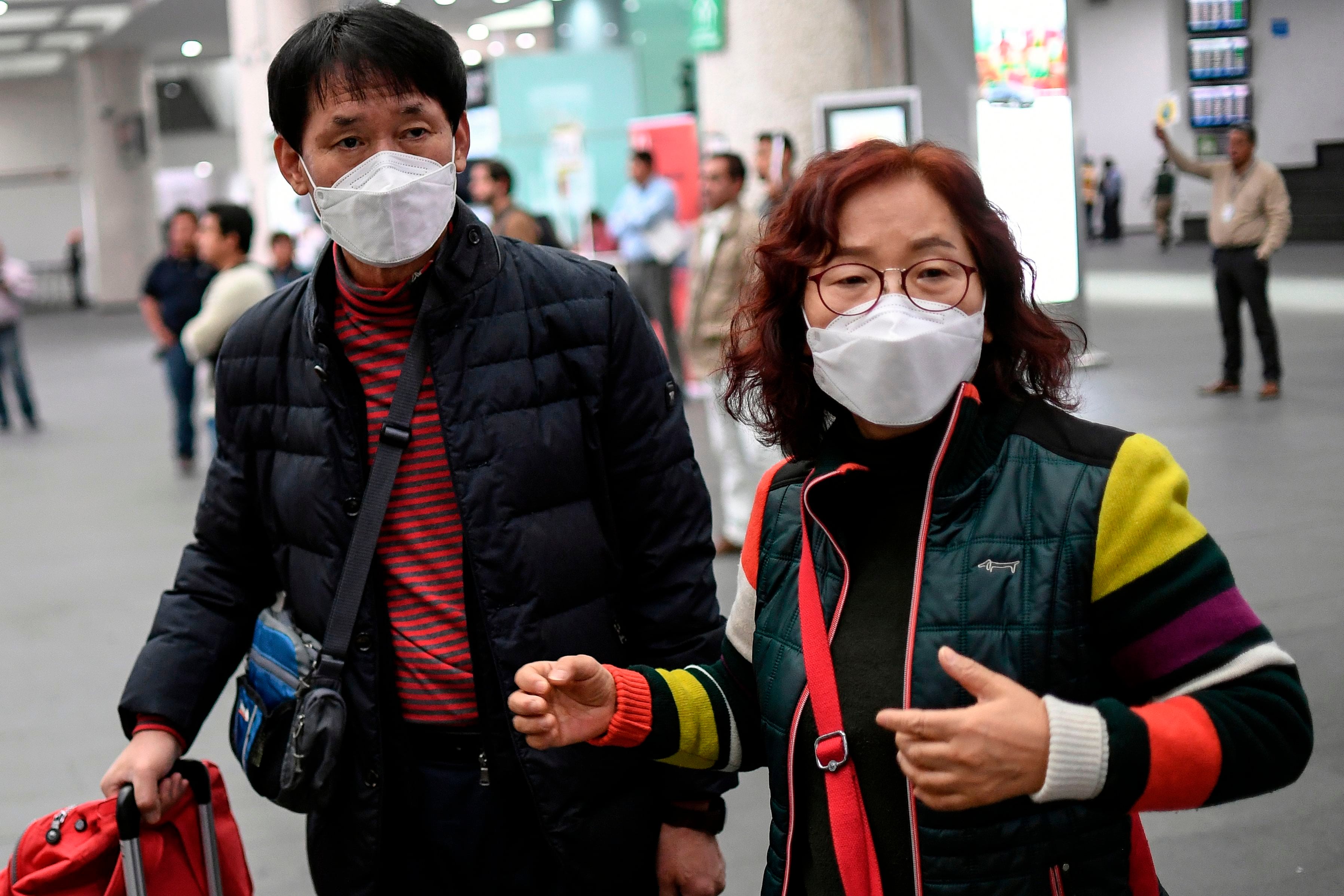 Dua penumpang mengenakan masker saat tiba di Bandara Internasional Mexico City, Meksiko