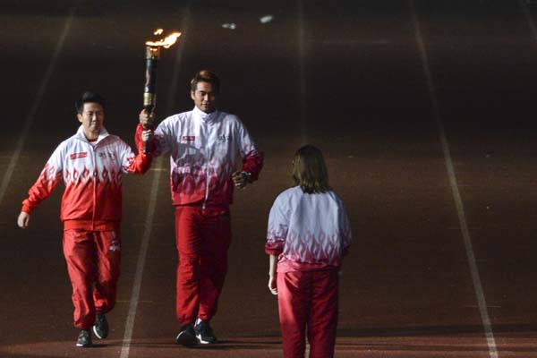 Pasangan pebulu tangkis peraih emas olimpiade Brasil Liliyana Natsir (kiri) dan Tontowi Ahmad (tengah) membawa obor api pon.
