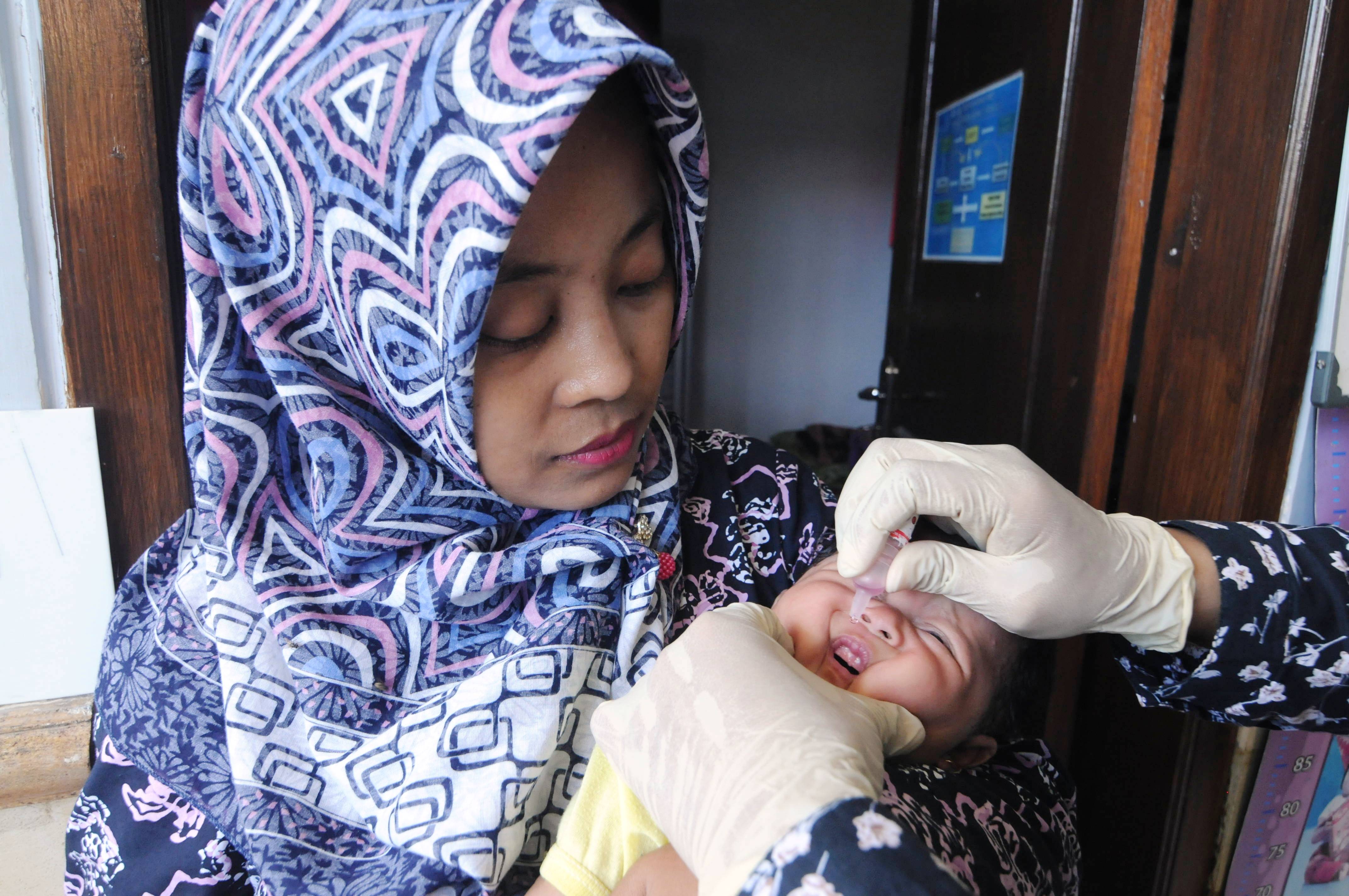 Bayi diberi imunisasi polio.
