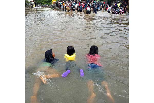 Anak-anak berenang berusaha menembus banjir di Jalan Raden Patah, Parung Serab, Ciledug, Tangerang, Banten, kemarin